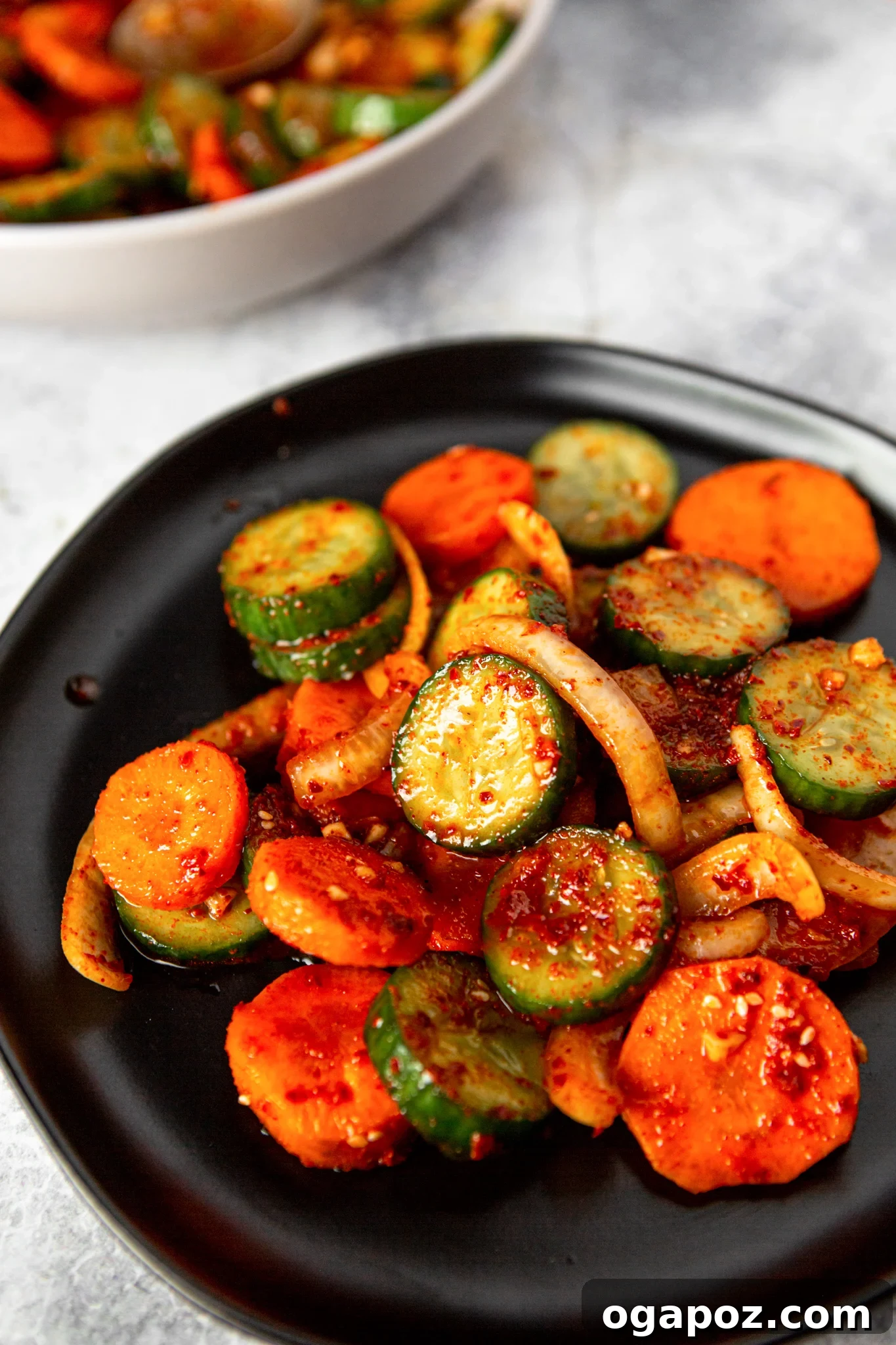 Instant Cucumber Kimchi 2 A black bowl filled with vibrant Quick Korean Cucumber Kimchi, showcasing the crisp cucumber slices and colorful ingredients, garnished with sesame seeds.