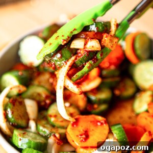 Instant Cucumber Kimchi 10 A vibrant dish of Quick Korean Cucumber Kimchi being served with tongs, ready to be enjoyed.