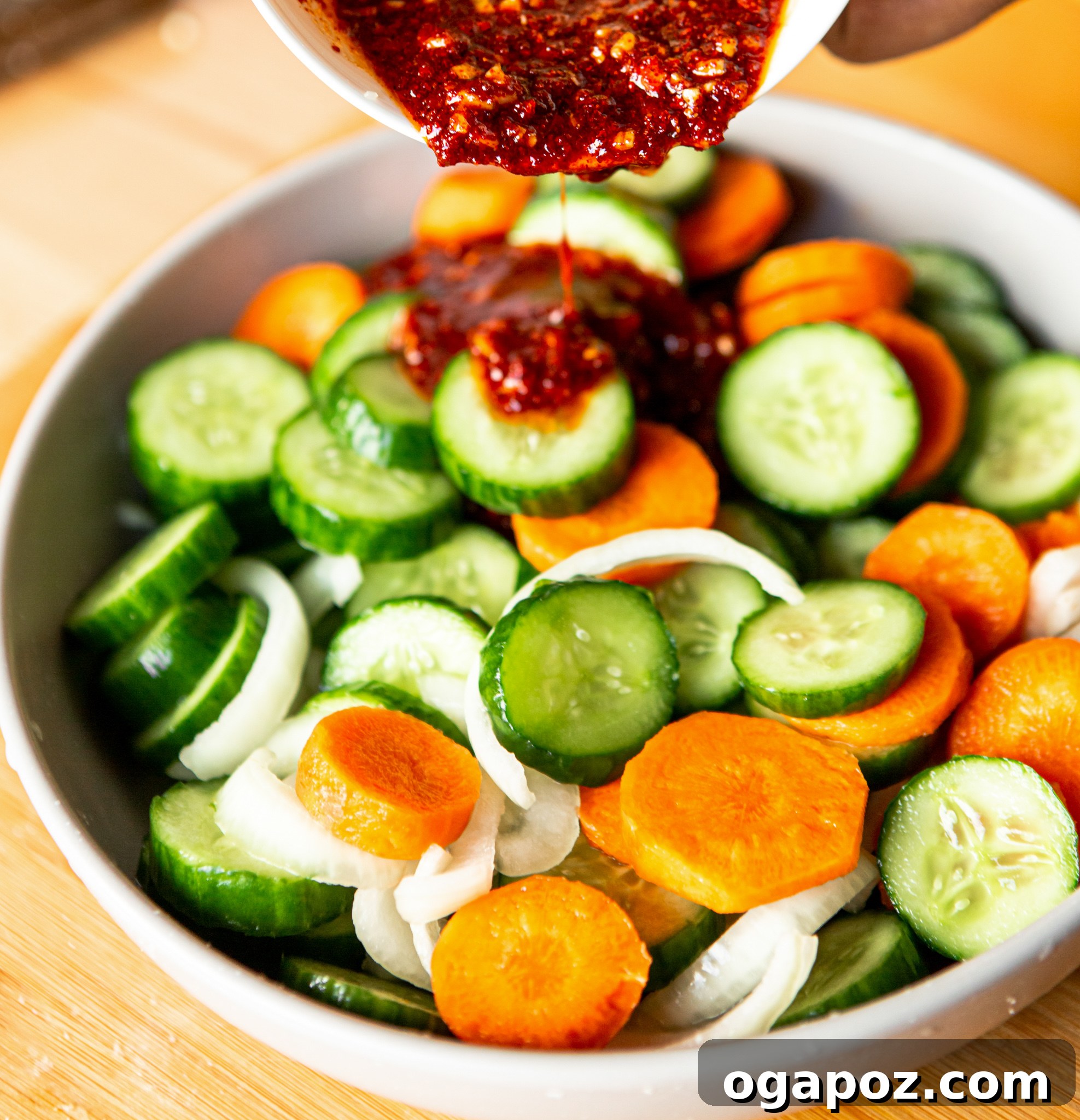 Instant Cucumber Kimchi 8 Quick Korean Cucumber Kimchi sauce being poured over prepared vegetables in a bowl, showcasing the vibrant colors before mixing.