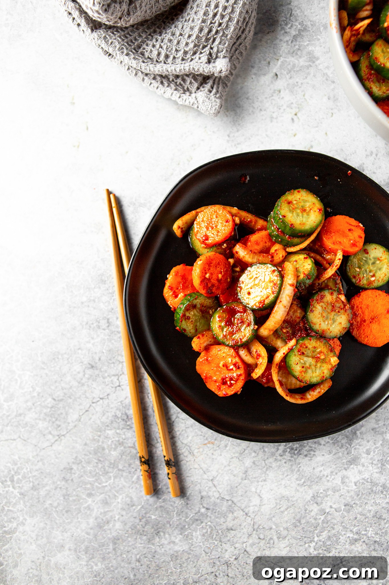 Instant Cucumber Kimchi 9 Quick Korean Cucumber Kimchi served in a black bowl with chopsticks, ready to be enjoyed as a refreshing side dish.