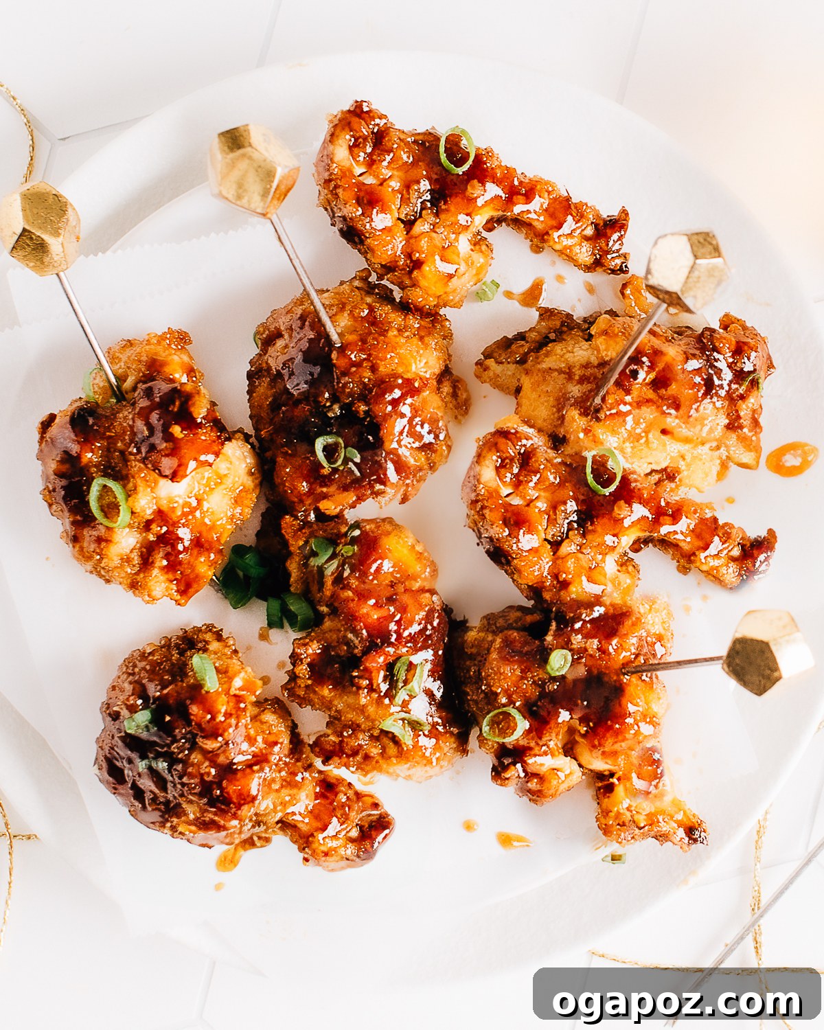 Sticky Glazed Crispy Cauliflower Wings 2 Crispy Cauliflower Wings coated in sticky sauce and garnished with green onions on a serving plate.