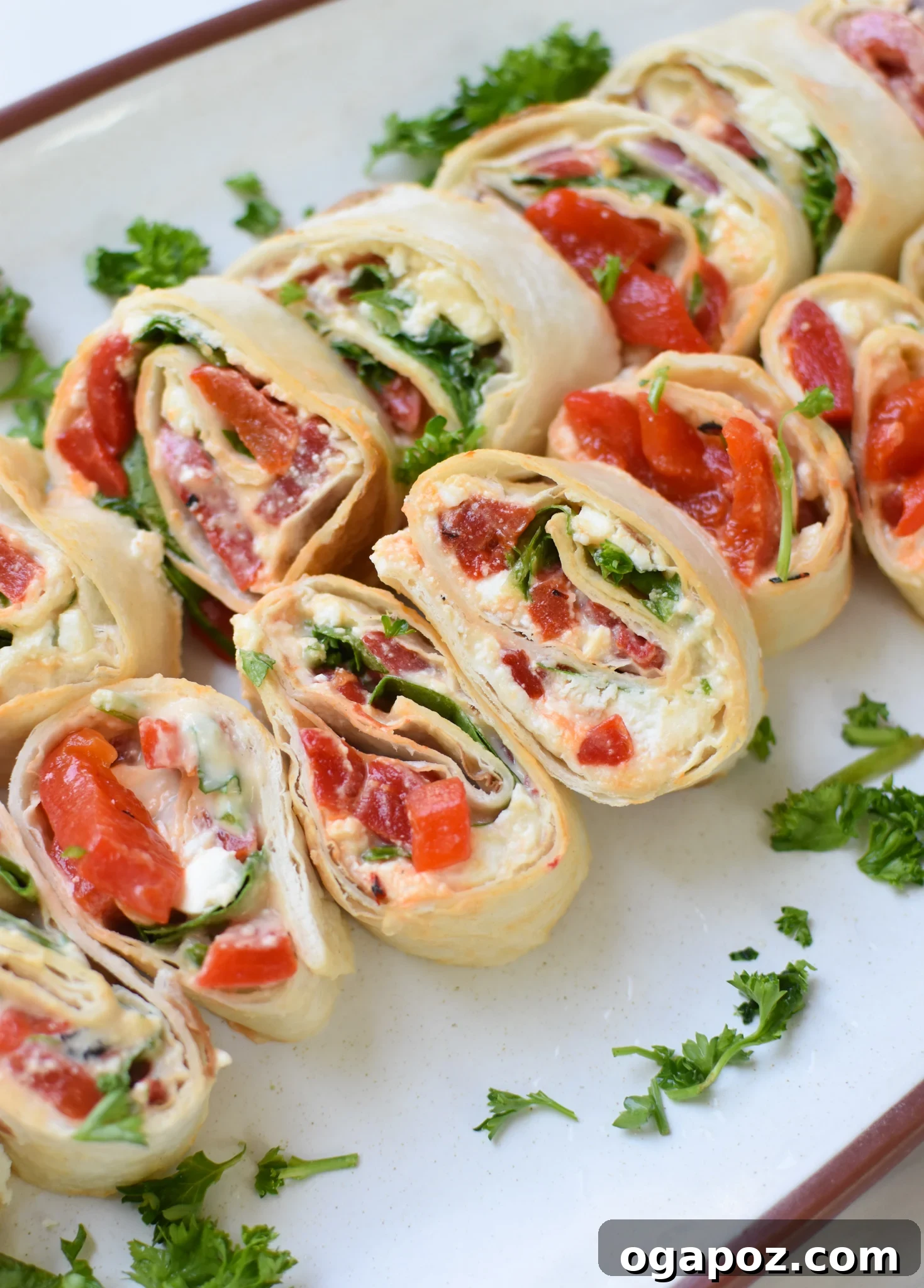 A plate of freshly cut Mediterranean Pinwheels, showcasing their vibrant colors and appealing spiral design.