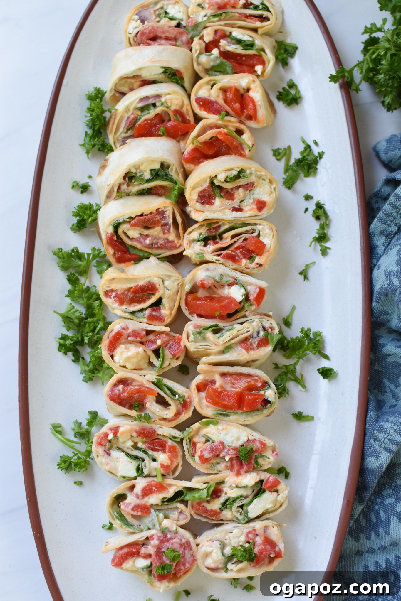 Mediterranean Pinwheels casually placed on a rustic wooden board, with a blue napkin nearby, emphasizing their casual elegance.