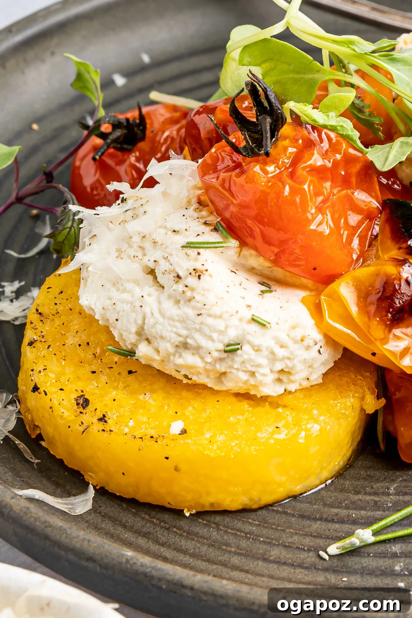 Golden Polenta Towers 2 Crispy Polenta Stacks topped with creamy ricotta and roasted cherry tomatoes, garnished with fresh herbs.