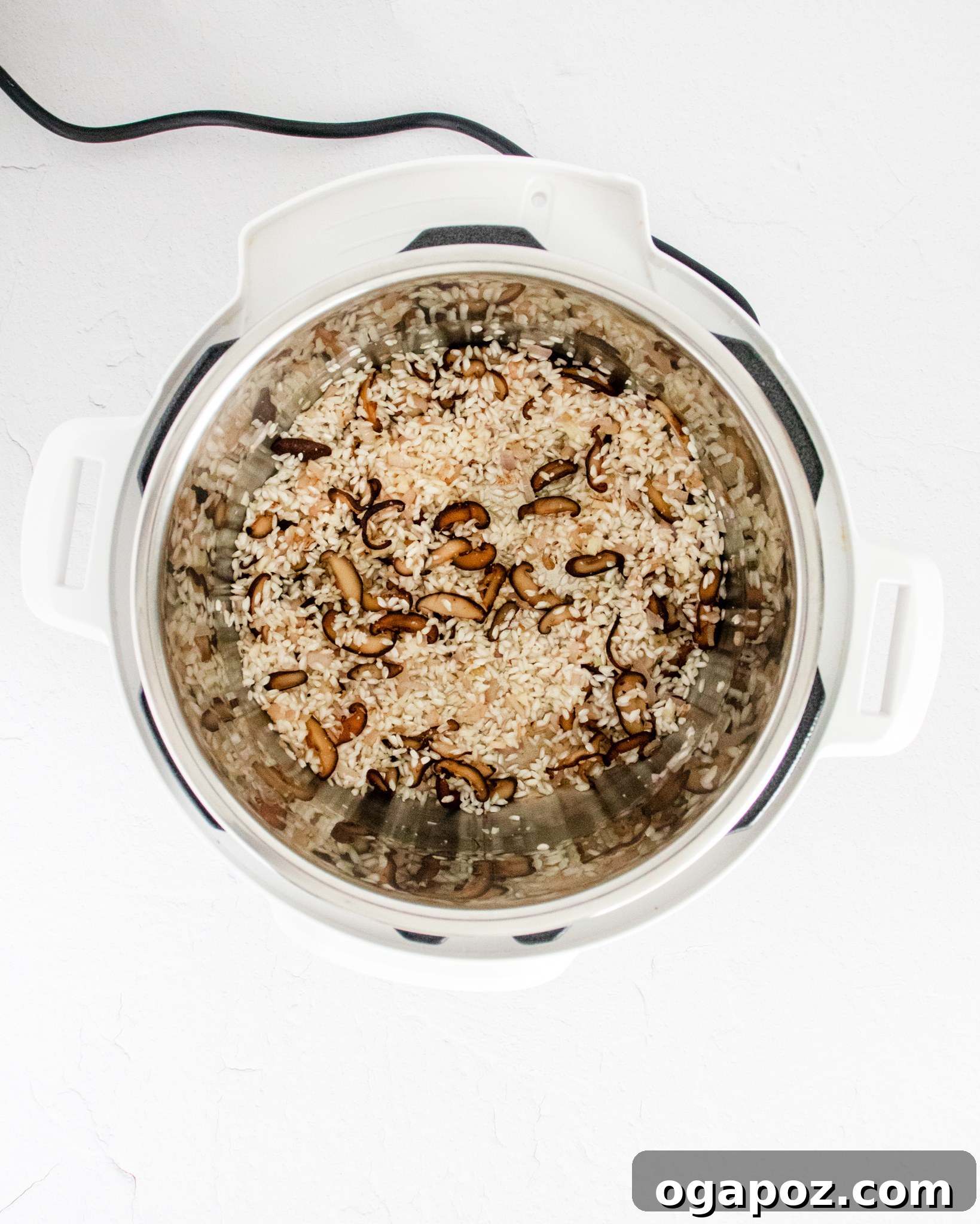 Creamy Instant Pot Mushroom Risotto 6 Adding chicken stock to the Instant Pot with sautéed ingredients and rice.