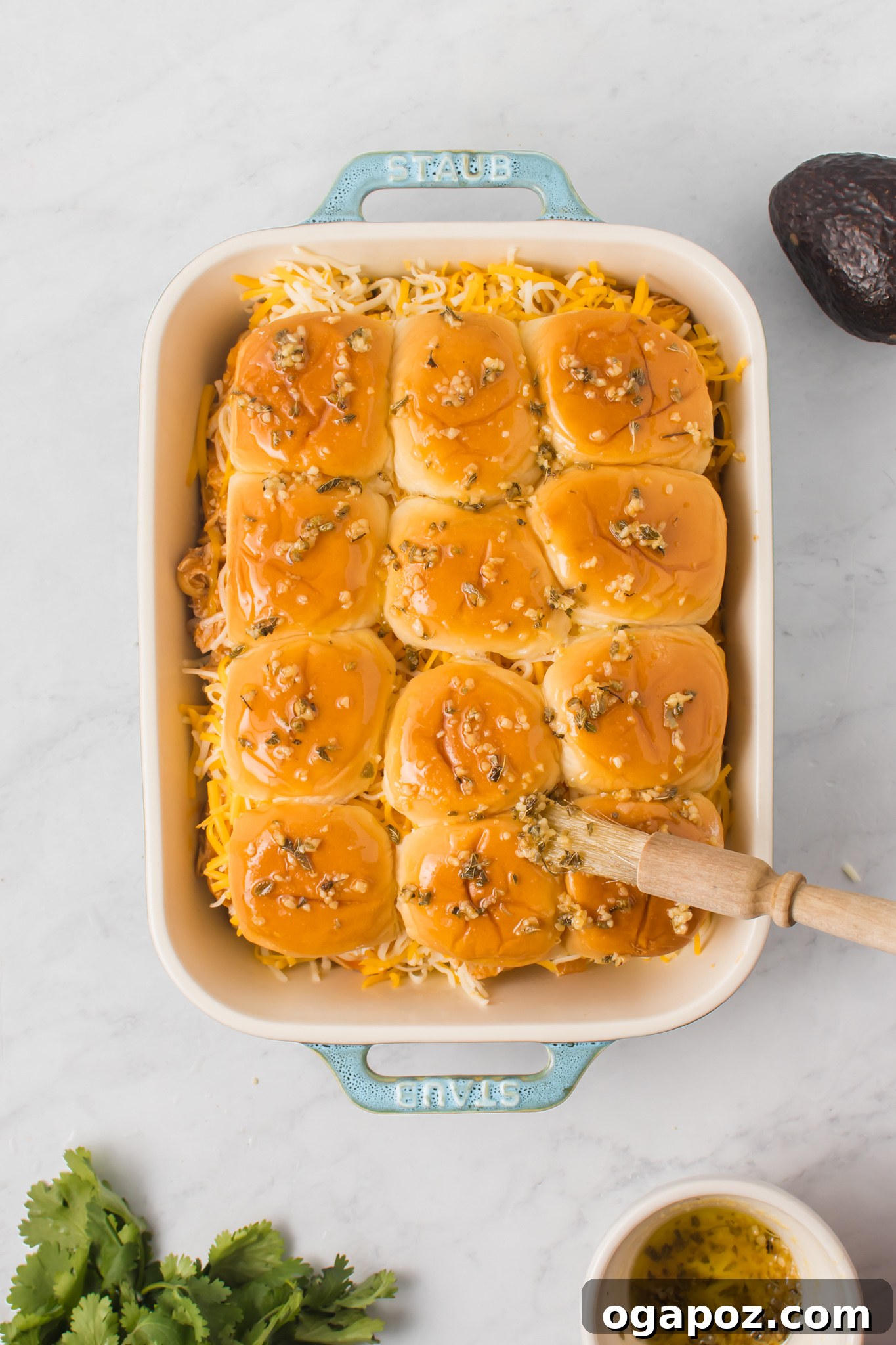Pull-Apart Chicken Enchilada Sliders 11 Close-up of Chicken Enchilada Sliders in a pan, brushed with herb butter and sprinkled with Mexican oregano.