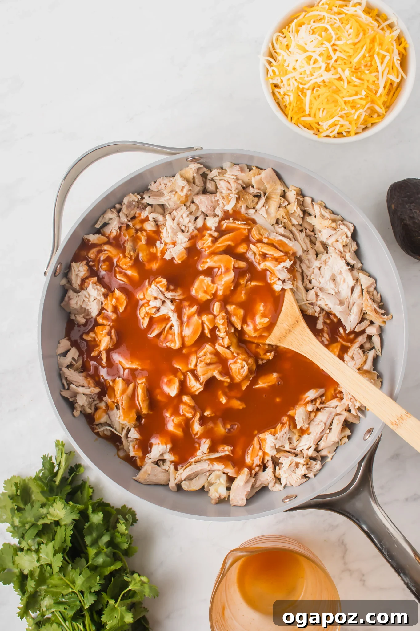 Pull-Apart Chicken Enchilada Sliders 6 Shredded chicken coated in rich red enchilada sauce simmering in a pan with sautéed onions and garlic.