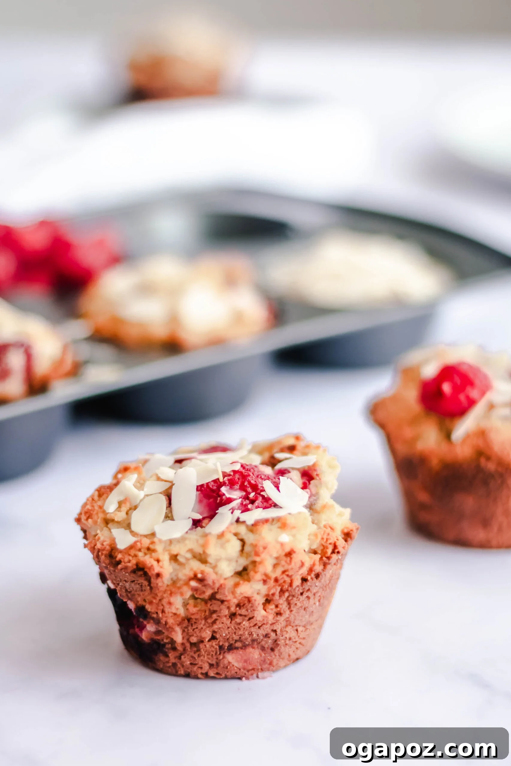 Delightful Keto Raspberry Muffins 2 Freshly baked Keto Raspberry Muffins with almonds on a cooling rack.