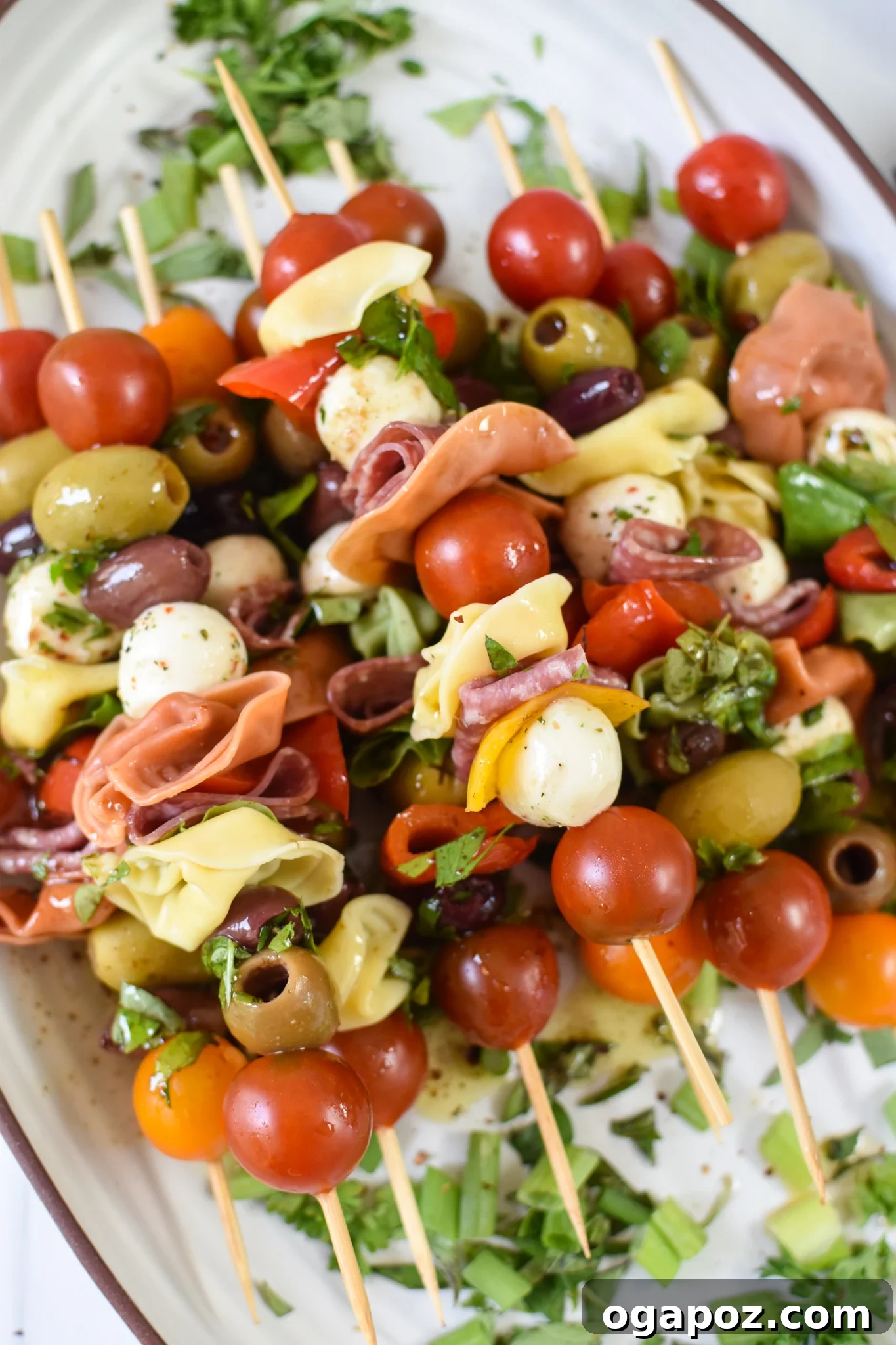 Flavorful Skewer Bites 2 Antipasto Skewers arranged beautifully on a white platter, showcasing vibrant colors of tomatoes, mozzarella, olives, and tortellini.