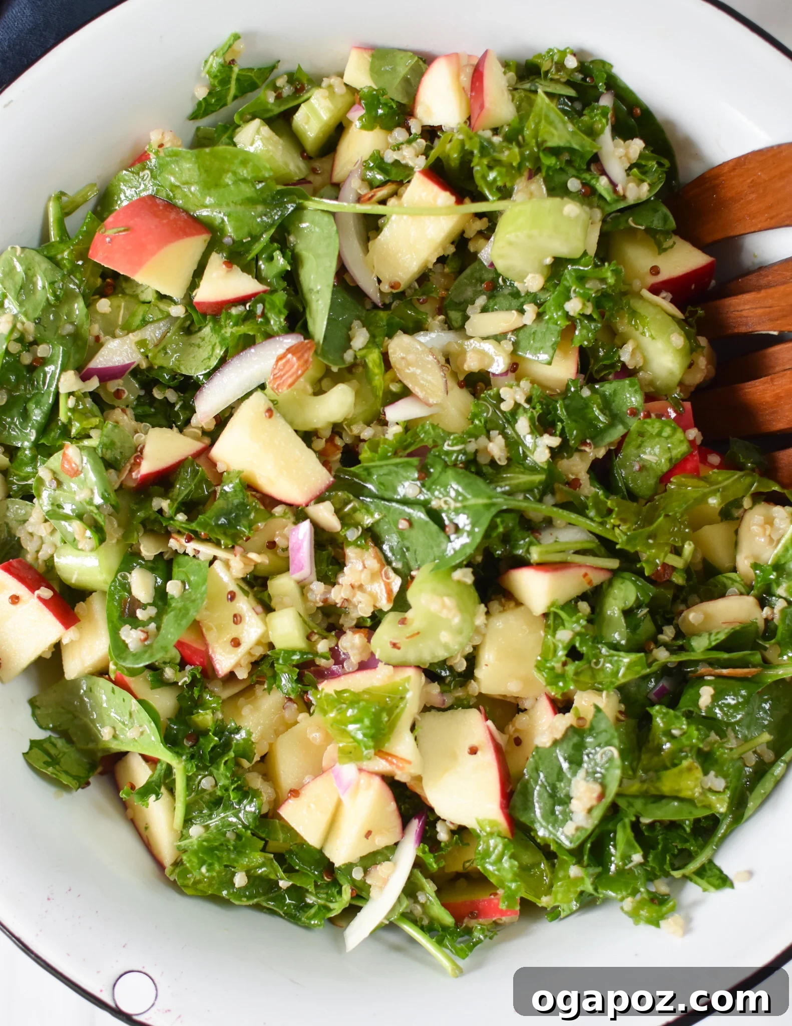 Vibrant Apple Kale Quinoa Medley 2 A vibrant Apple Kale Quinoa Salad served in a large wooden bowl, garnished with fresh herbs and wooden serving spoons, perfect for a fall meal.