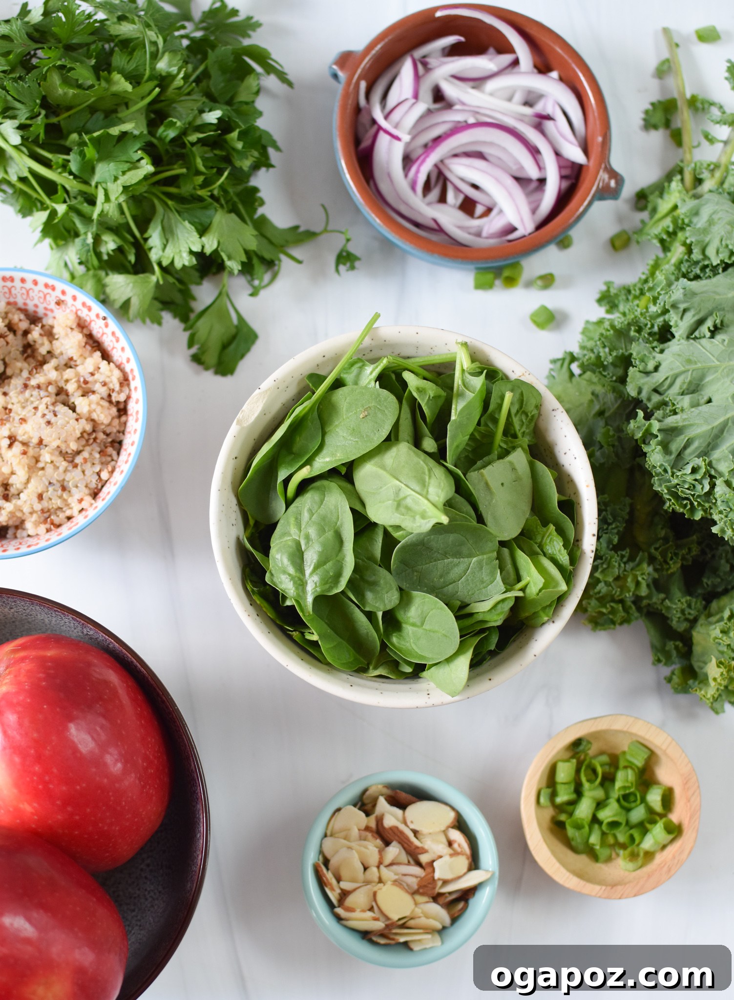 Vibrant Apple Kale Quinoa Medley 3 A vibrant selection of fresh ingredients for Apple Kale Quinoa Salad, including green kale, red apples, sliced red onion, almonds, and cooked white quinoa, arranged on a wooden surface.