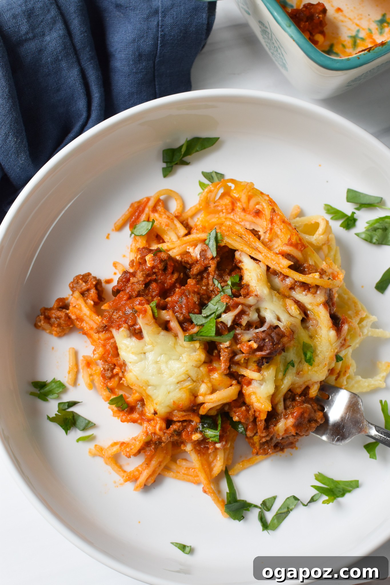 Hearty Baked Spaghetti Casserole 2 Spaghetti Pie Recipe on a white plate, showcasing a slice with layers of pasta, meat sauce, and cheese.