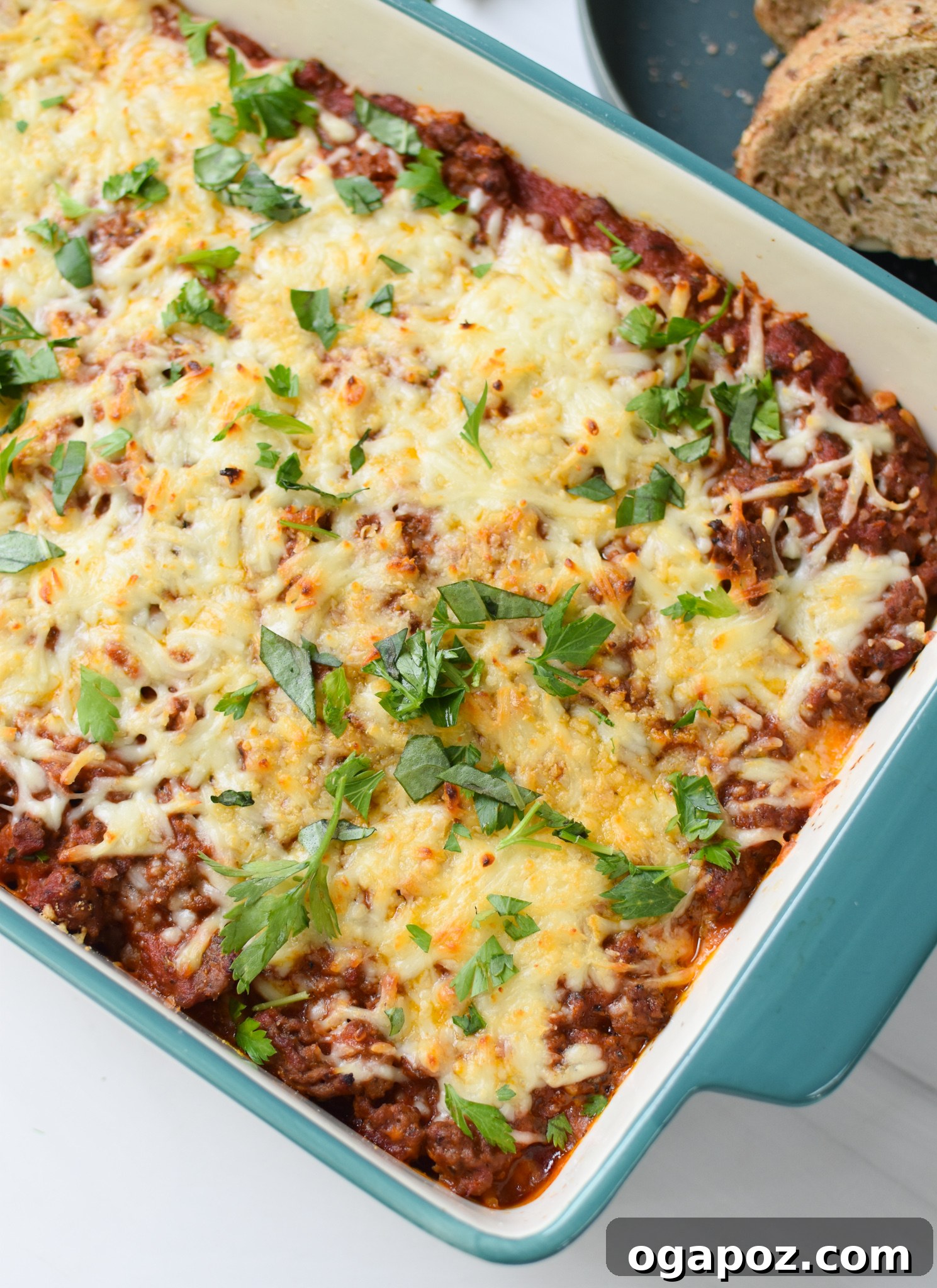 Hearty Baked Spaghetti Casserole 6 Spaghetti Pie Recipe in a teal baking dish, fresh out of the oven, garnished with herbs.