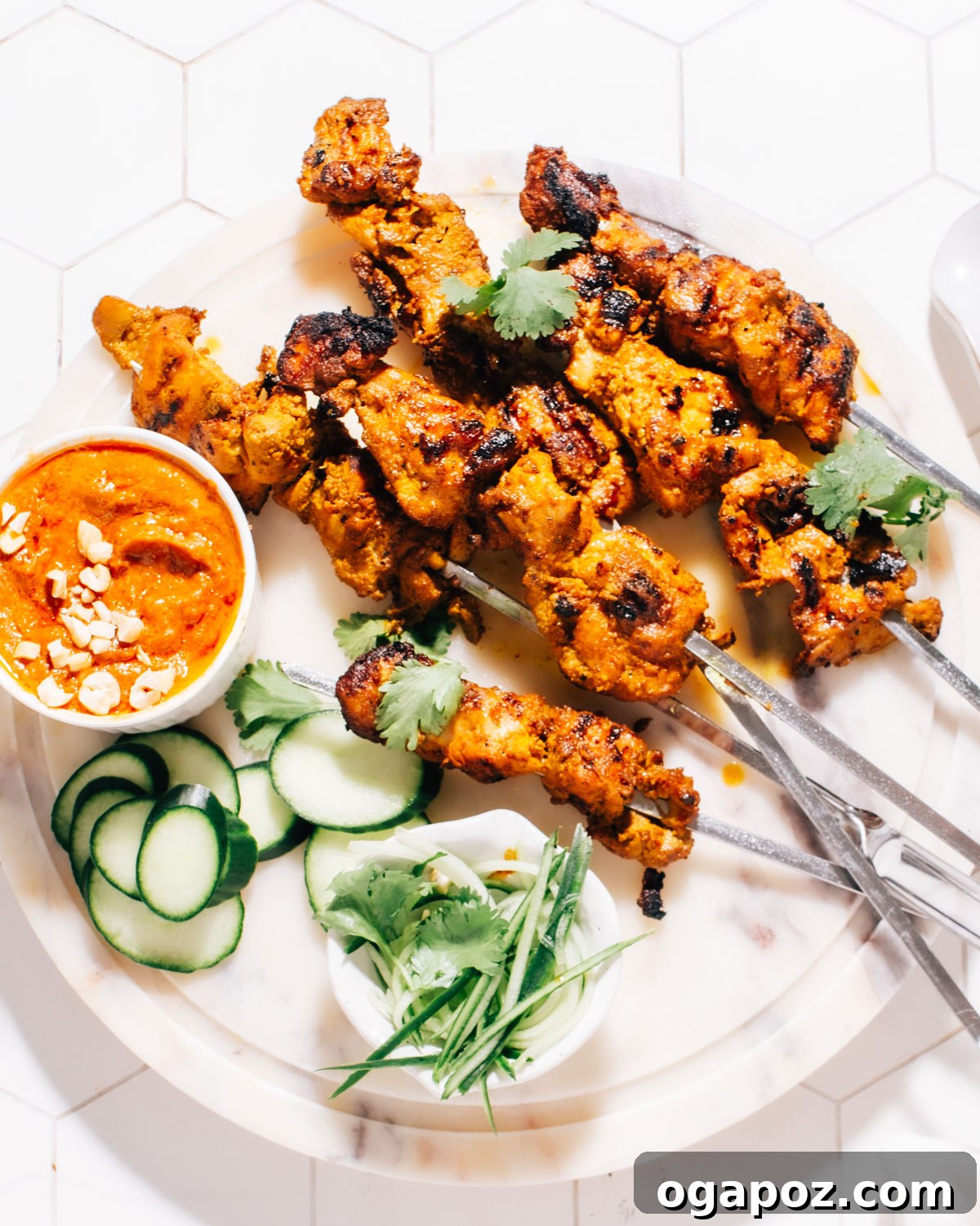 Irresistible Thai Satay Skewers 2 Grilled Thai Satay chicken skewers served with a rich peanut sauce on a plate, garnished with fresh herbs.