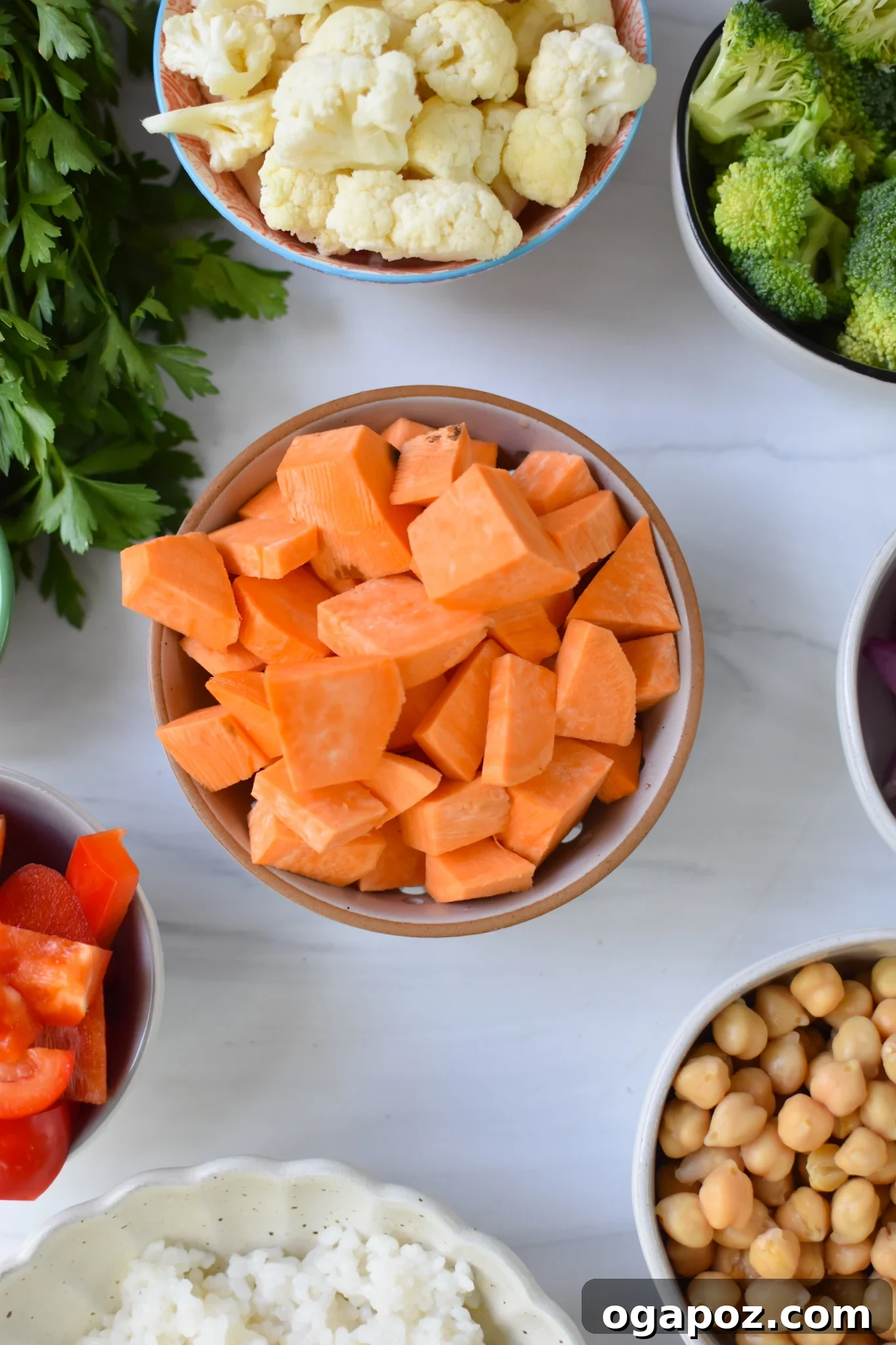Wholesome Sweet Potato Bowl 3 Fresh ingredients laid out for a Sweet Potato Bowl recipe including sweet potatoes, broccoli, cauliflower, carrots, red onion, bell pepper, chickpeas, rice, and tahini dressing components.