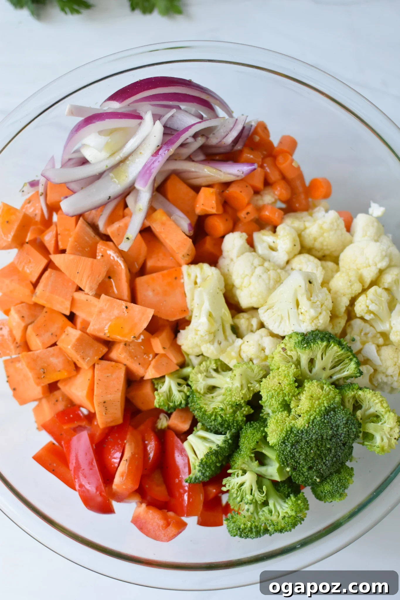 Wholesome Sweet Potato Bowl 5 Diced sweet potatoes, broccoli, cauliflower, carrots, red onion, and red bell pepper tossed with olive oil and spices in a large mixing bowl, ready for roasting.