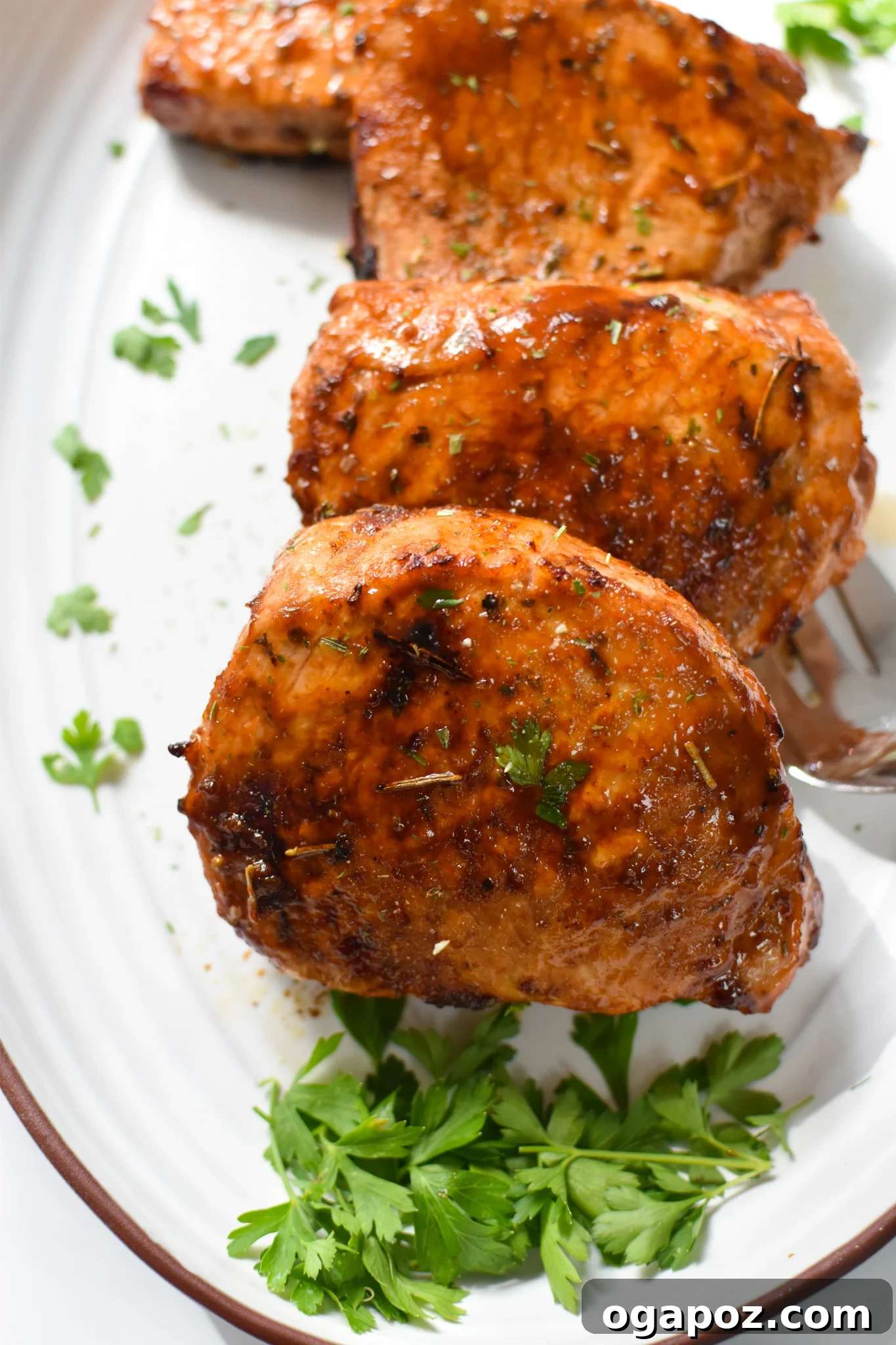 Effortless Air Fryer Boneless Pork Chops 2 Beautifully cooked Air Fryer Boneless Pork Chops served on a pristine white platter, garnished with fresh herbs.