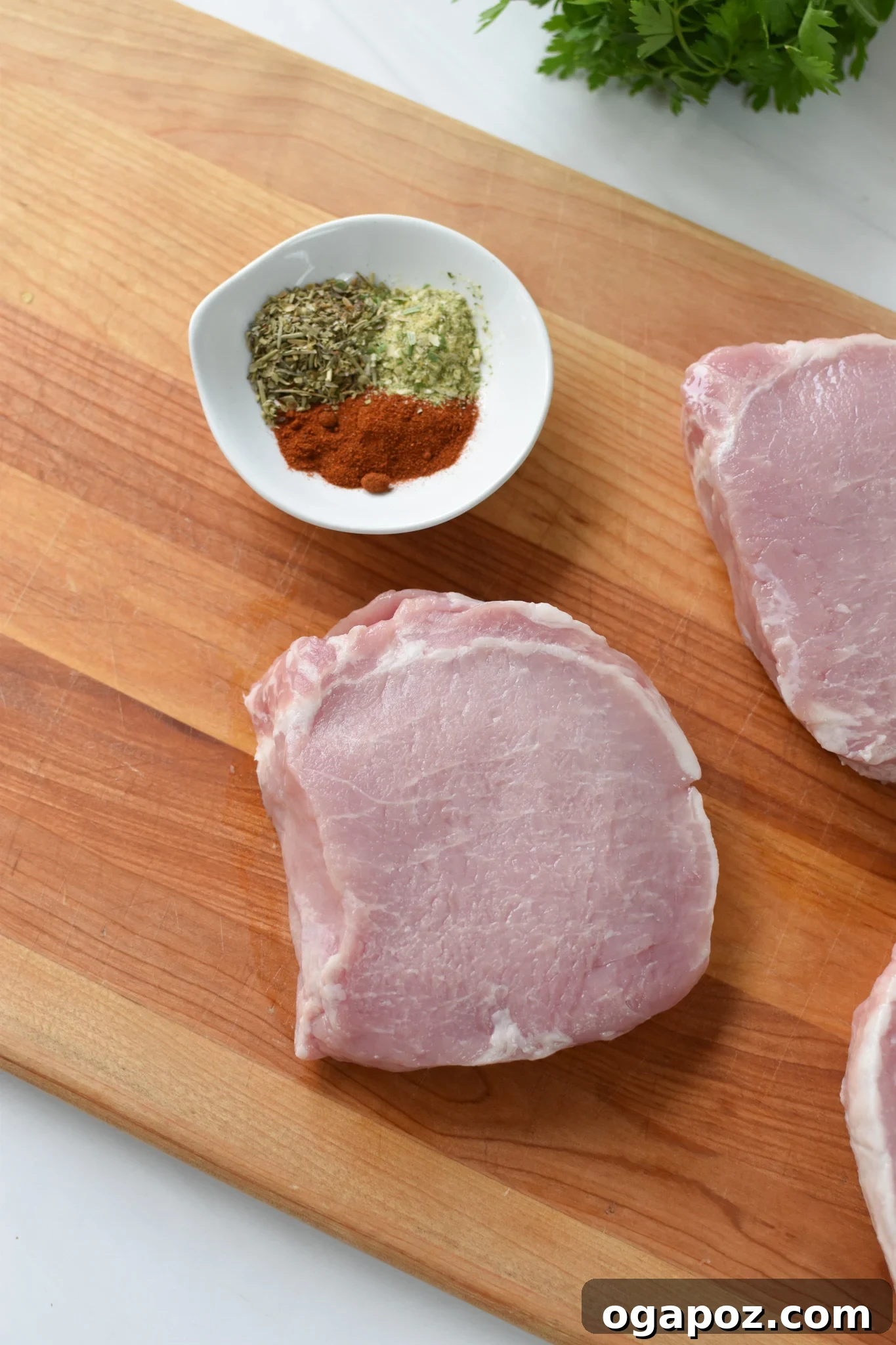 Effortless Air Fryer Boneless Pork Chops 4 Raw boneless pork chops laid out on a cutting board, ready for seasoning and drying with paper towels.
