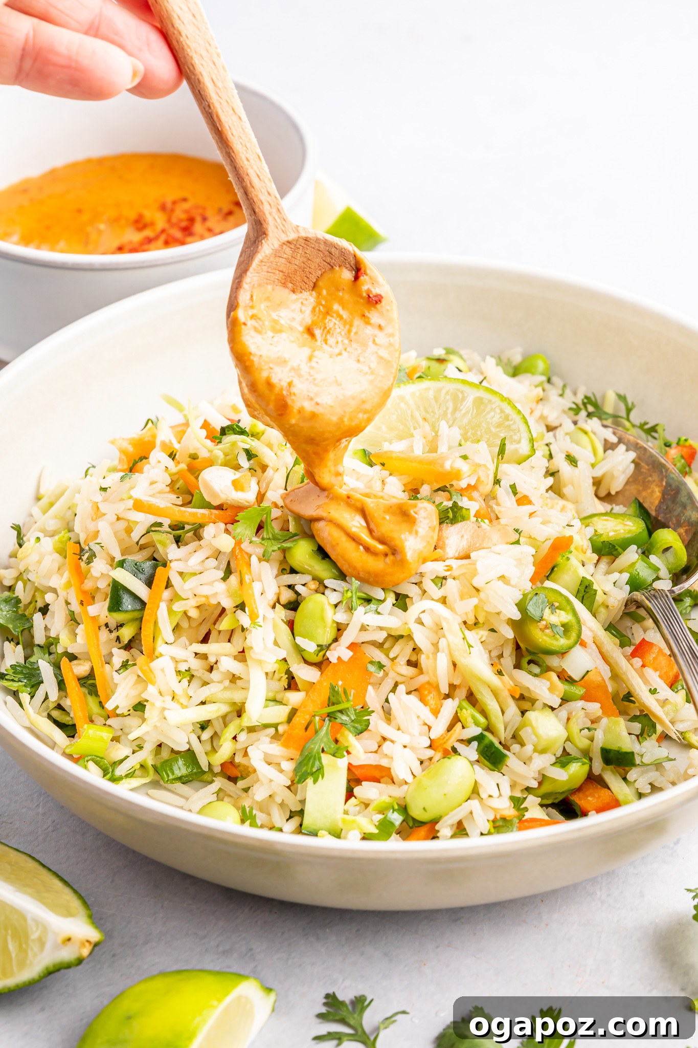 Tropical Coconut Rice Salad 7 Peanut dressing being poured generously over the Coconut Rice Salad in a large bowl.
