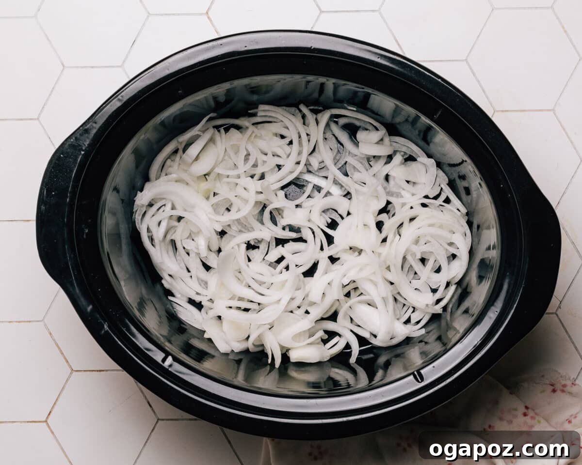 Melt-in-Your-Mouth Slow Cooker BBQ Chicken 4 Step 1: Spreading sliced onions at the bottom of a slow cooker to create a flavor base for Crockpot BBQ Chicken.