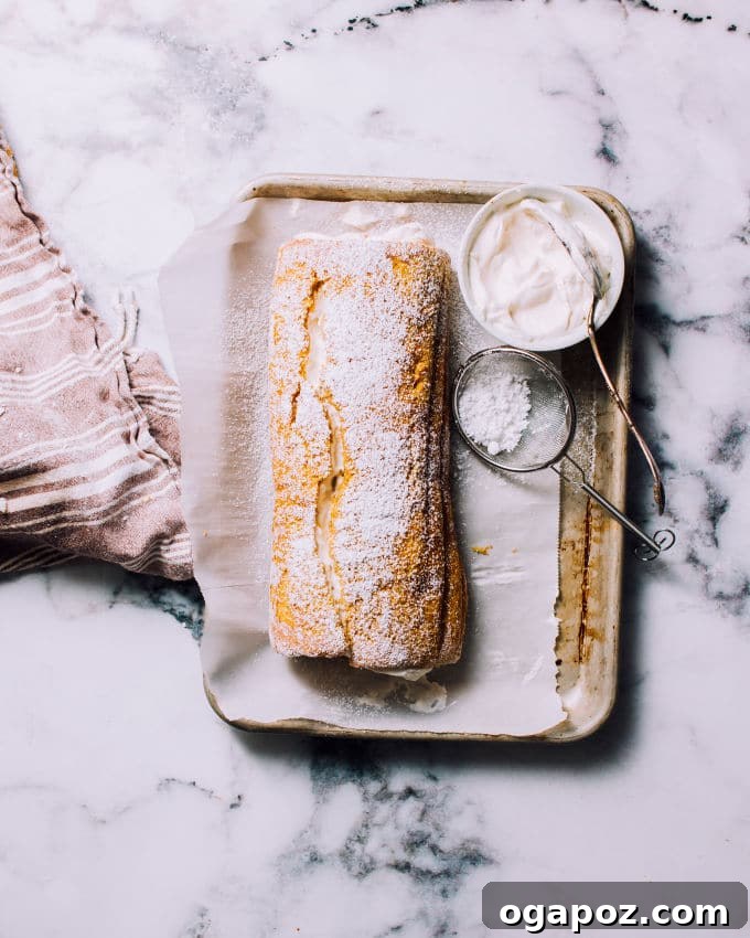 Close-up of a perfectly sliced pumpkin roll cake with smooth layers of cake and cream cheese filling.