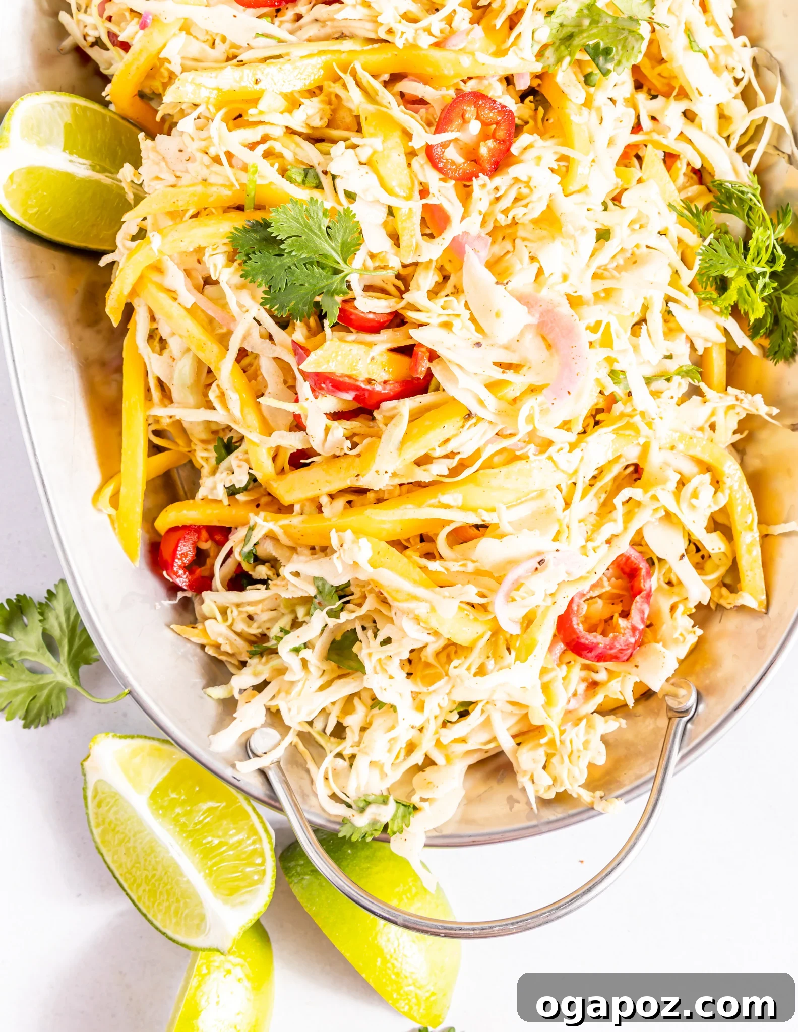 Easy Caribbean Coleslaw Recipe on a white platter, garnished with fresh herbs.
