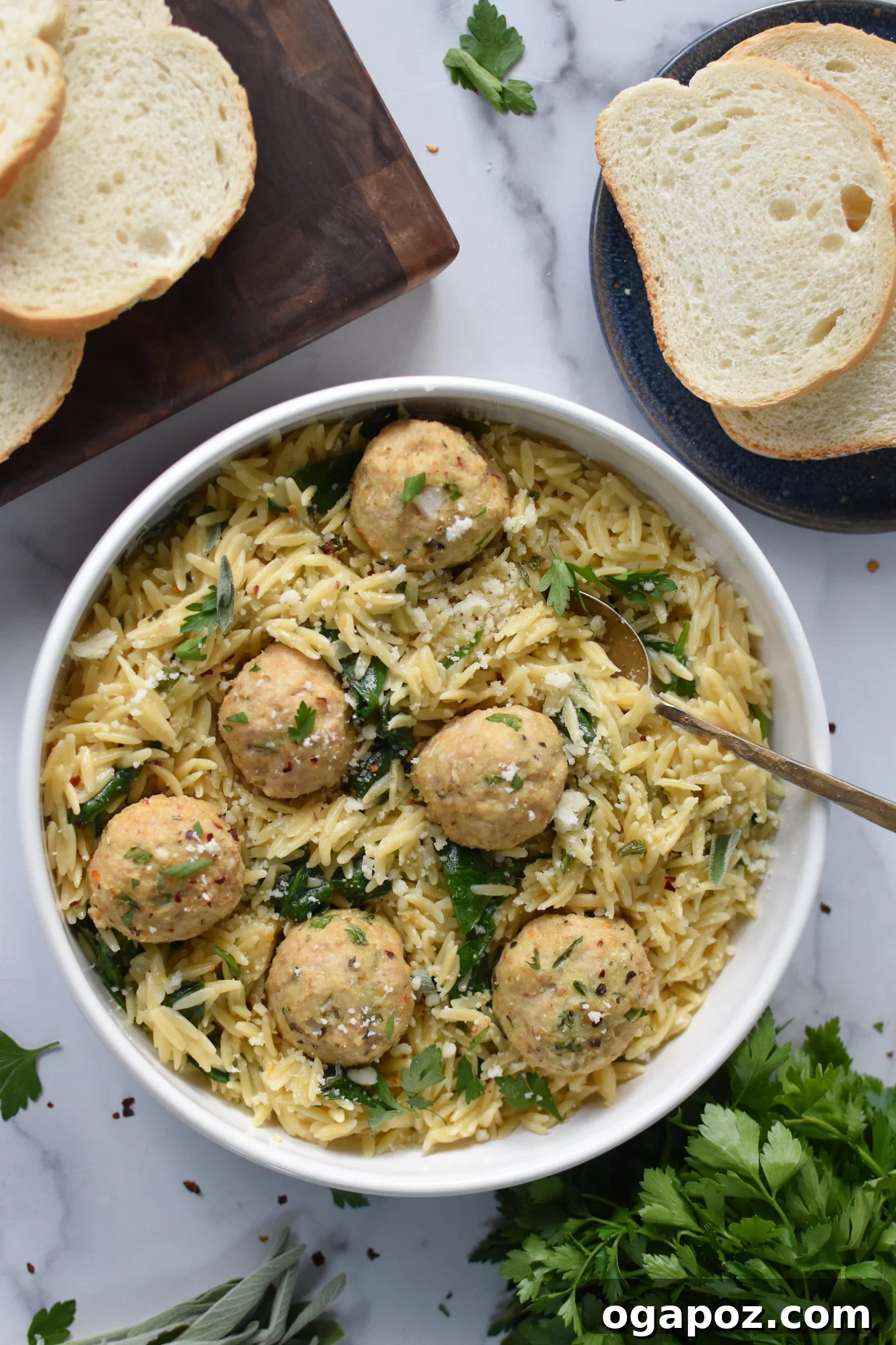 Delicious baked chicken meatballs in a white bowl, with a fork ready to serve alongside creamy orzo.