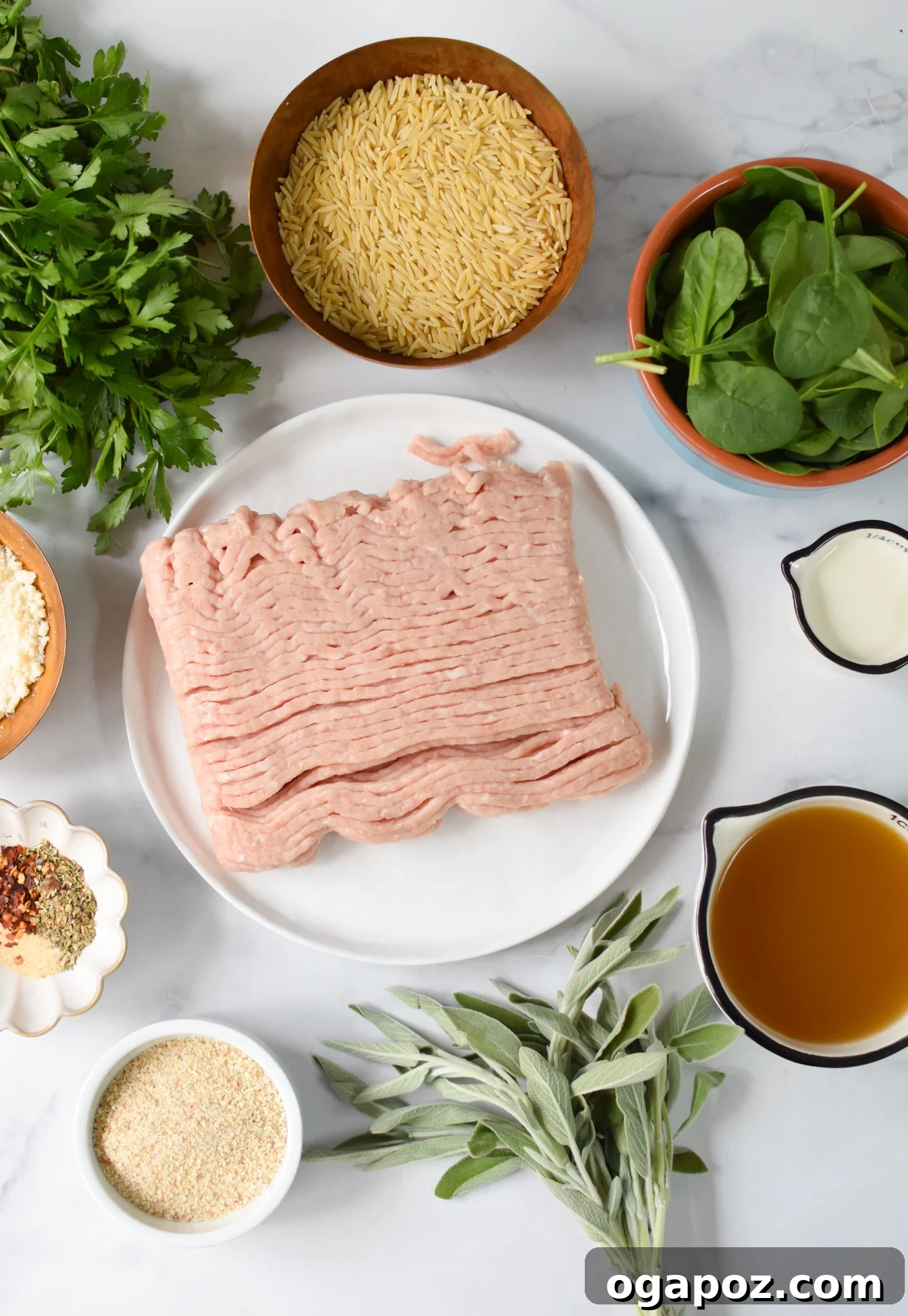 A selection of fresh ingredients for baked chicken meatballs including ground chicken, herbs, and spices.