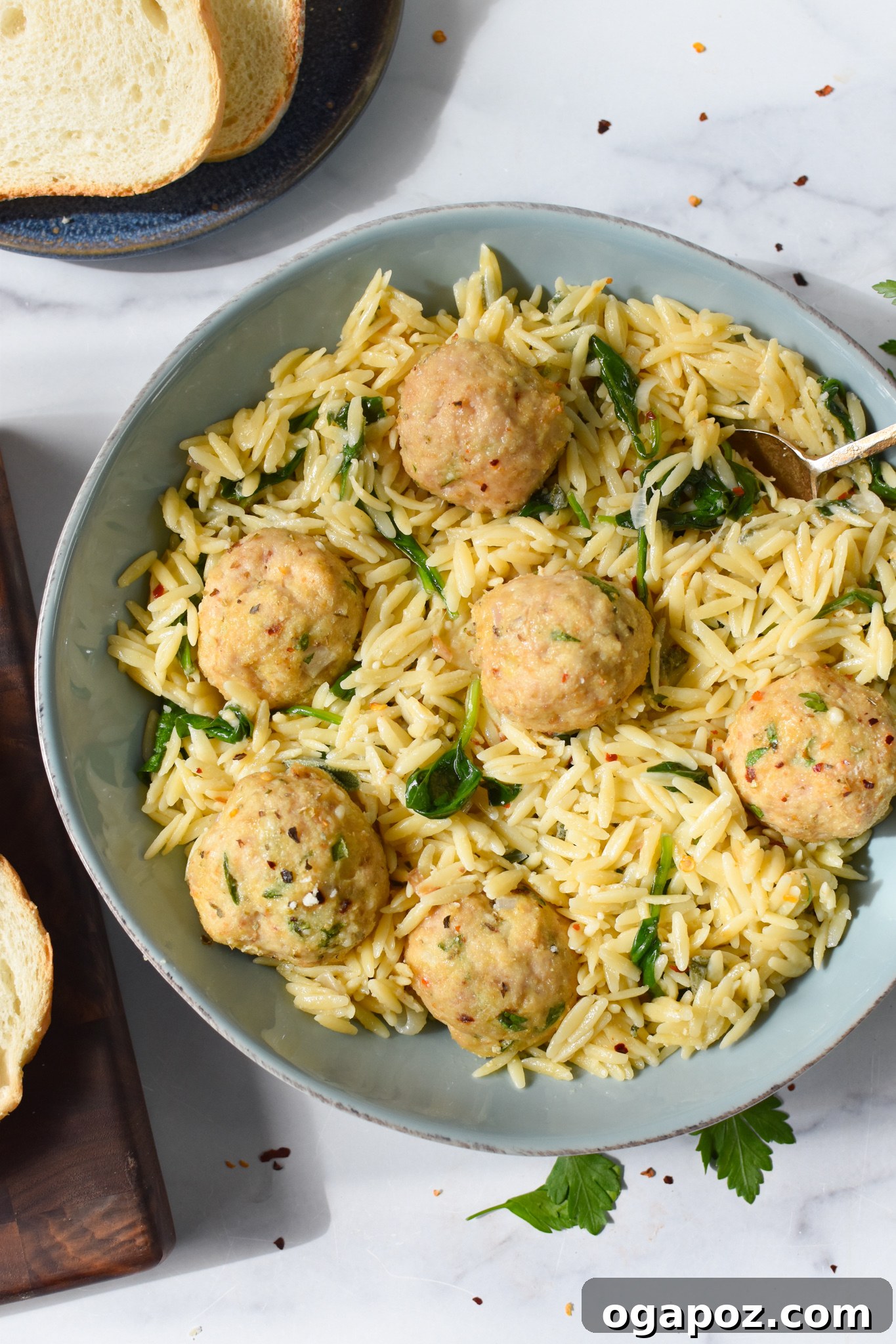 Cooked baked chicken meatballs resting in a blue serving bowl, garnished with fresh herbs.