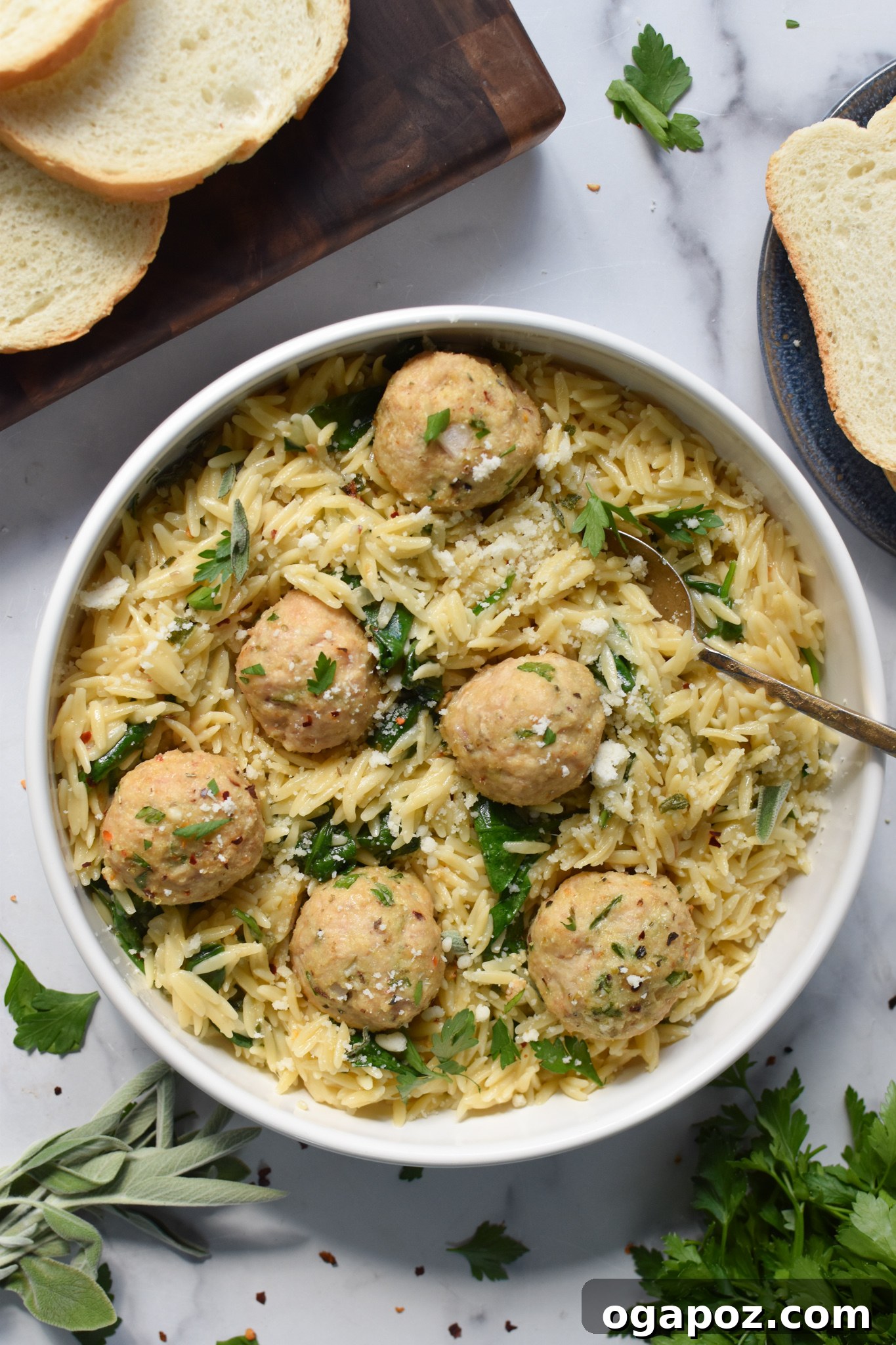 Baked chicken meatballs served with creamy orzo in a bowl, with a fork digging in.