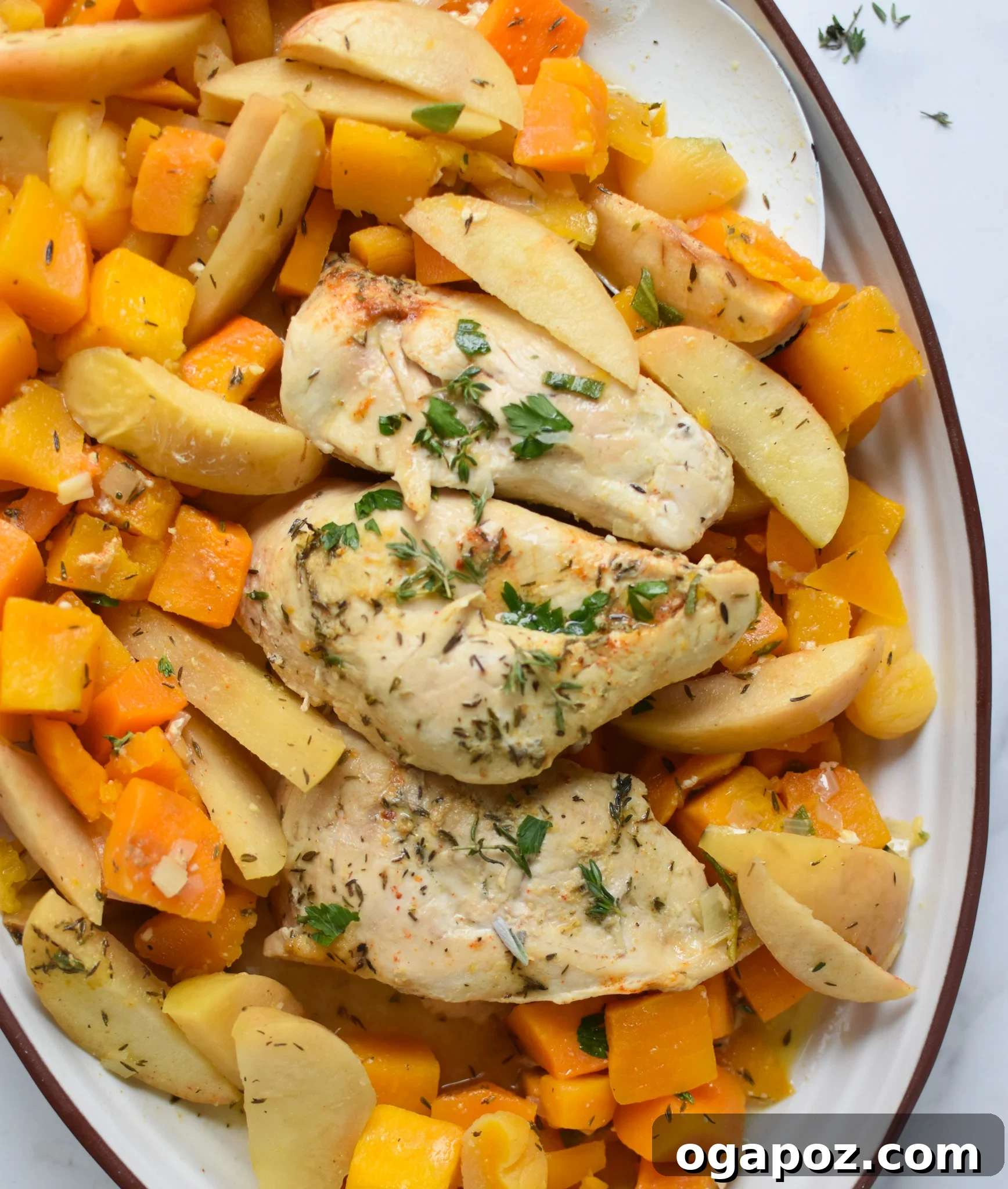 Sweet and Savory Slow Cooker Apple Chicken 4 A close-up view of Crockpot Apple Chicken Breast Recipe served on a white plate, garnished with fresh herbs, showcasing the rich sauce and tender ingredients.