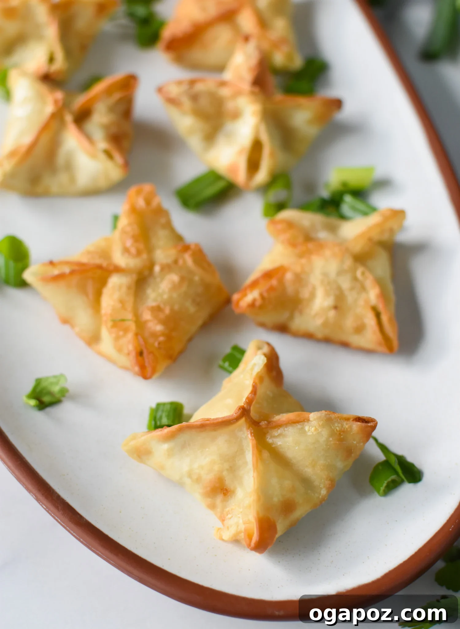 Crispy Air Fryer Crab Rangoon 2 Golden-brown Air Fryer Crab Rangoon on a white platter, ready to be served.