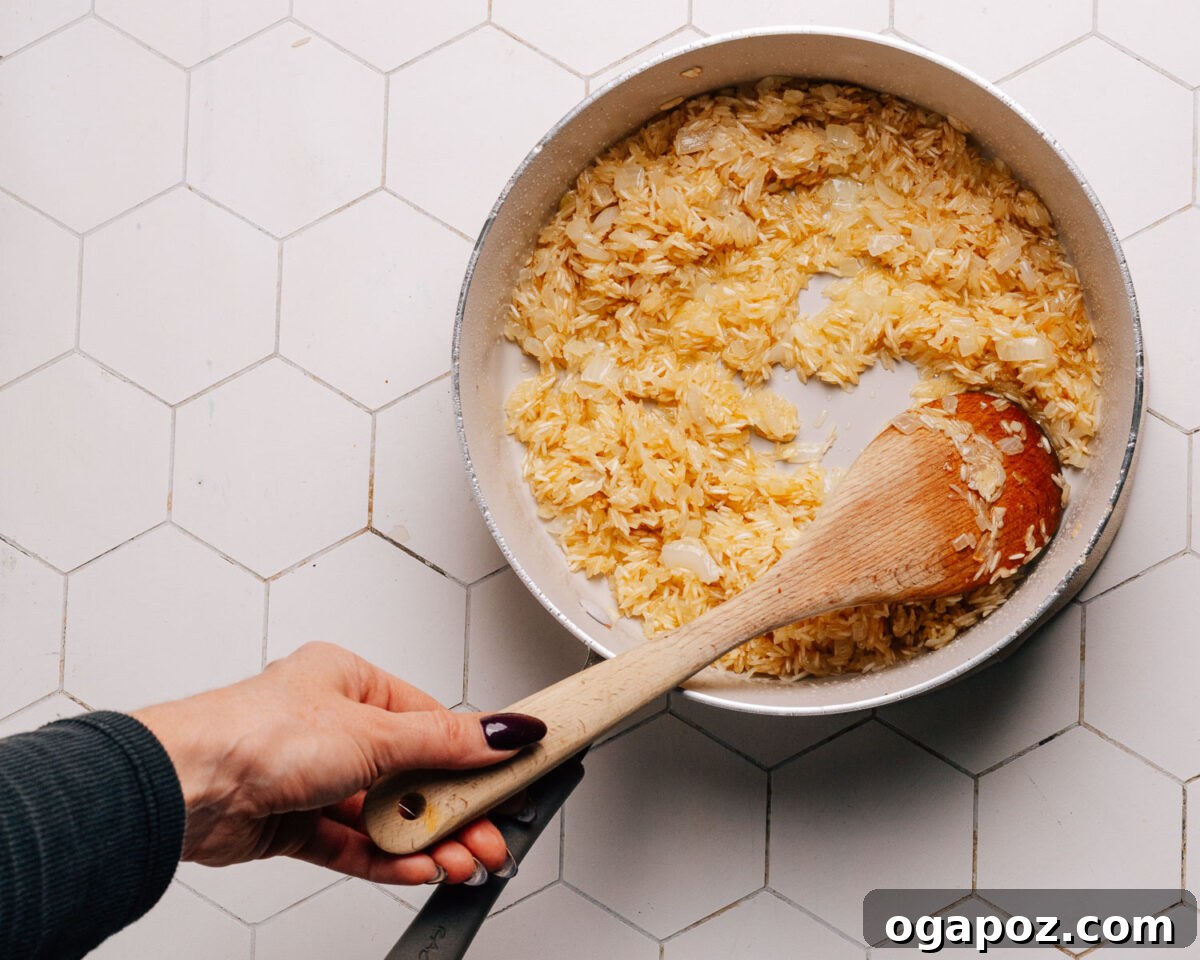 Effortless Chicken and Rice Delight 7 Step 4: Uncooked rice is added to the skillet with butter and aromatics, being toasted for added flavor.