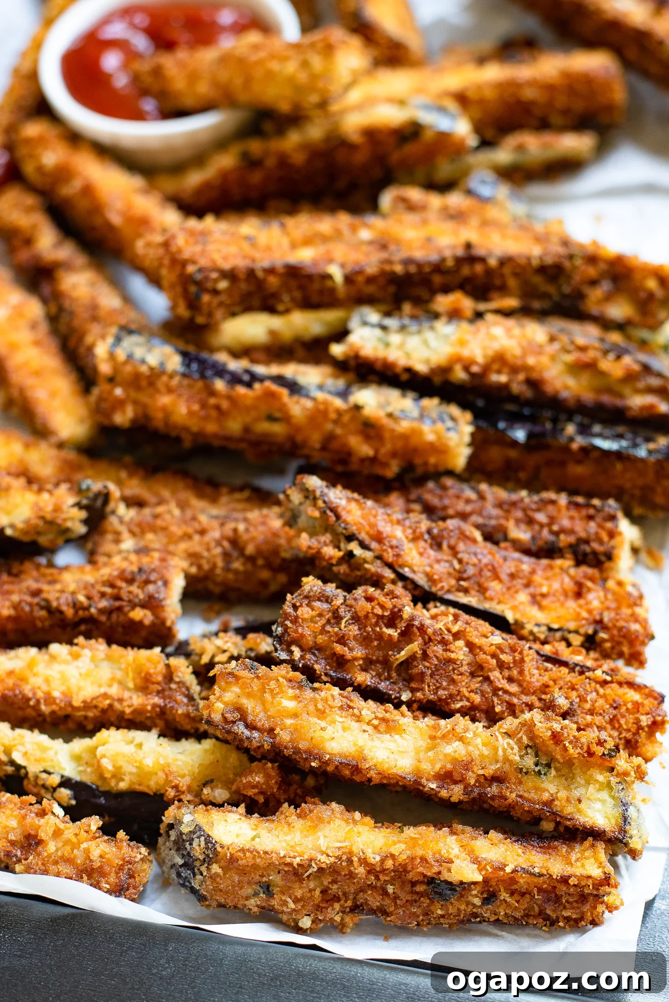 Irresistible Air Fryer Eggplant Fries 2 Crispy Air Fryer Eggplant Fries served on parchment paper with a dipping sauce.