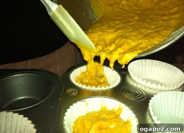 Spatula In A baker carefully filling a muffin pan with rich carrot cupcake batter using a rubber spatula
