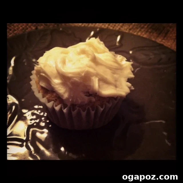 Final Cupcake A perfectly frosted carrot cupcake, showcasing its delicious cream cheese frosting and appealing texture with a sprinkle of cinnamon