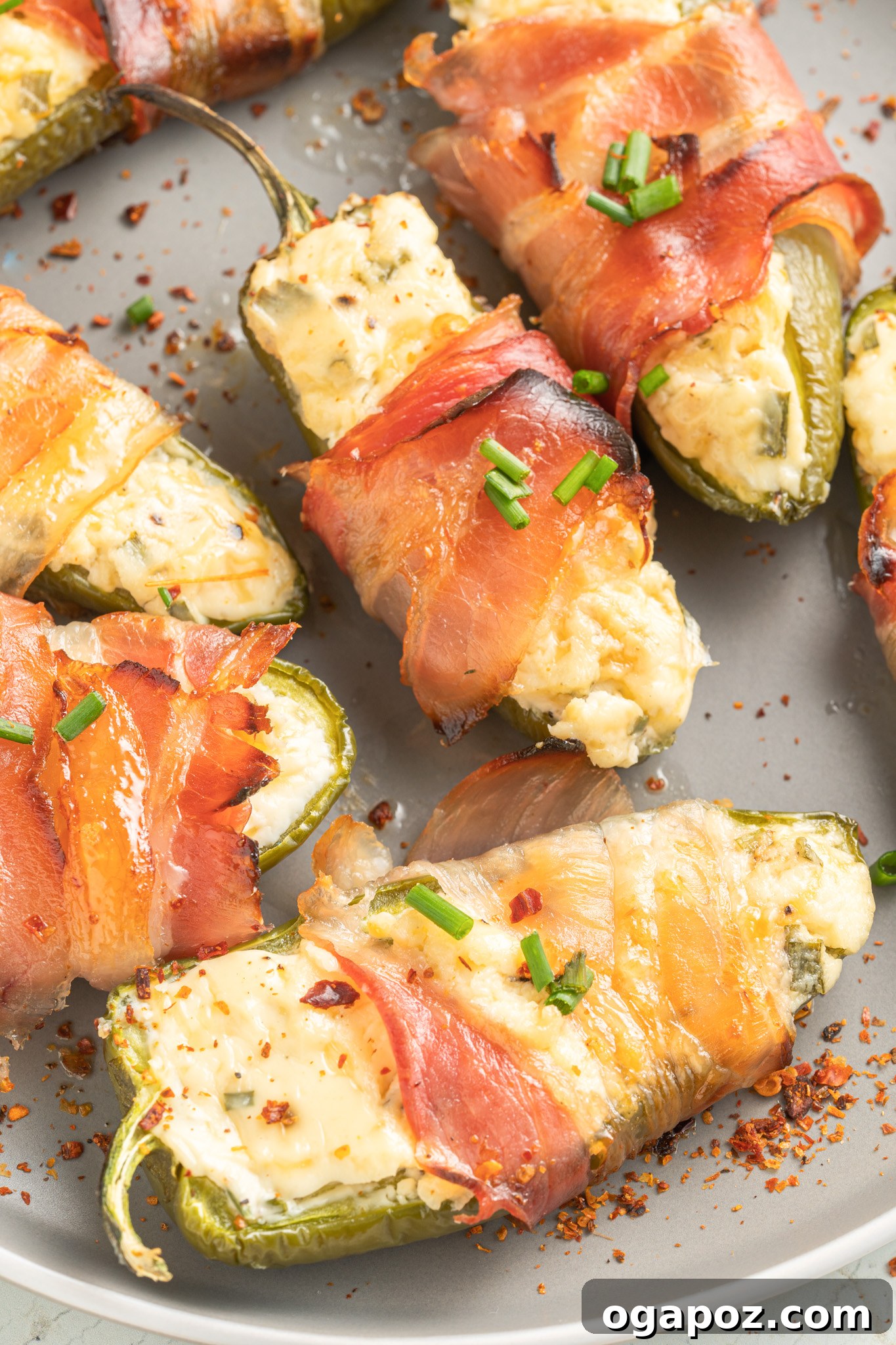 Bacon-Wrapped Jalapeño Bombs 2 Perfectly baked Jalapeño Poppers with Bacon, golden and crispy, arranged on a grey serving plate.