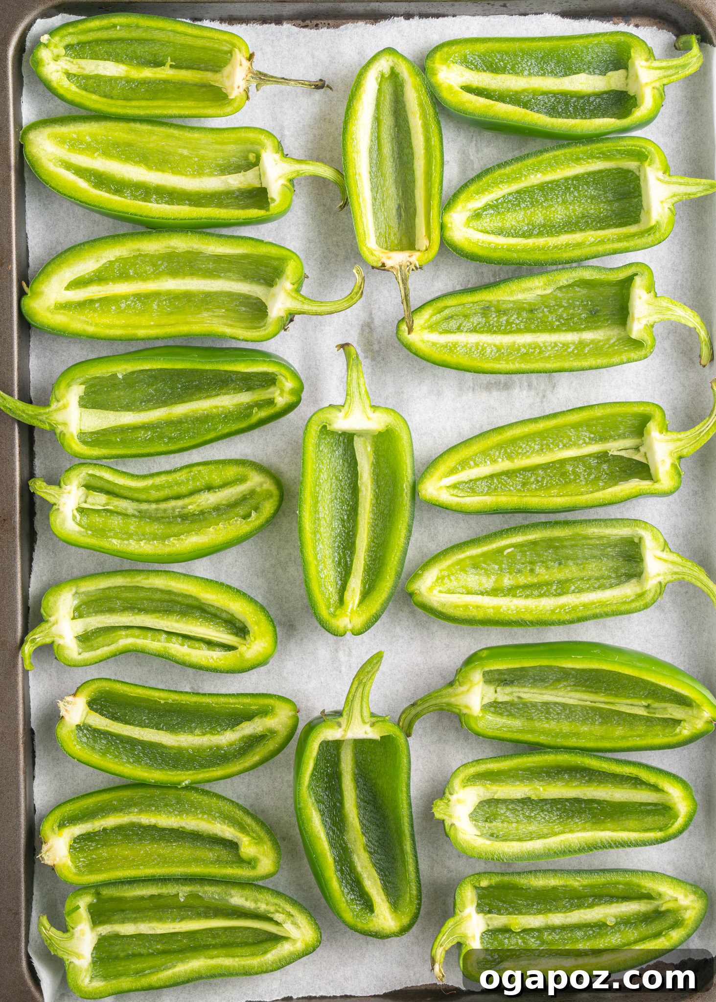 Bacon-Wrapped Jalapeño Bombs 5 Halved and deseeded jalapeños arranged on a parchment-lined baking sheet, ready for filling.