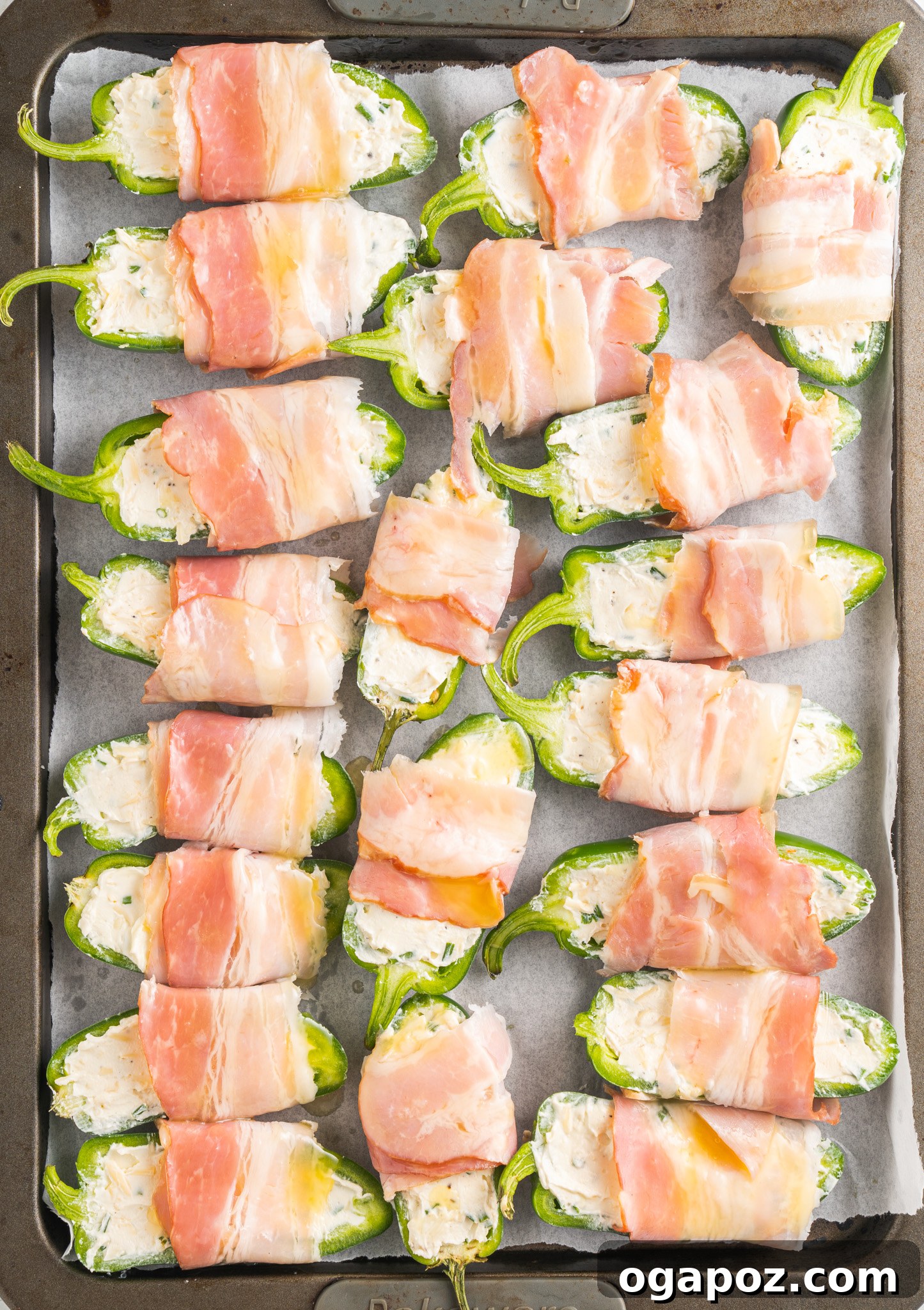 Bacon-Wrapped Jalapeño Bombs 10 Freshly baked Jalapeño Poppers with Bacon on a parchment-lined baking sheet, hot from the oven.