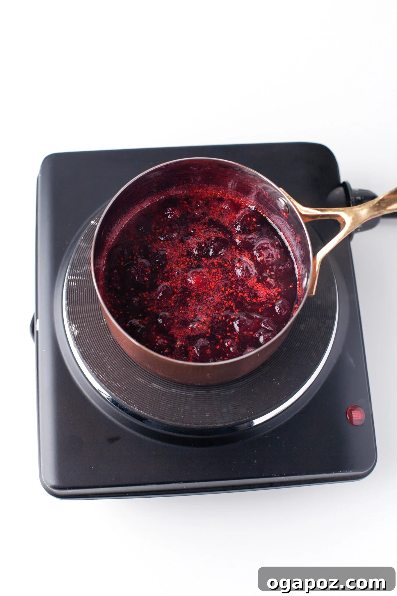 Fresh cranberries simmering in a pot, the beginning of homemade cranberry syrup for a festive cocktail.