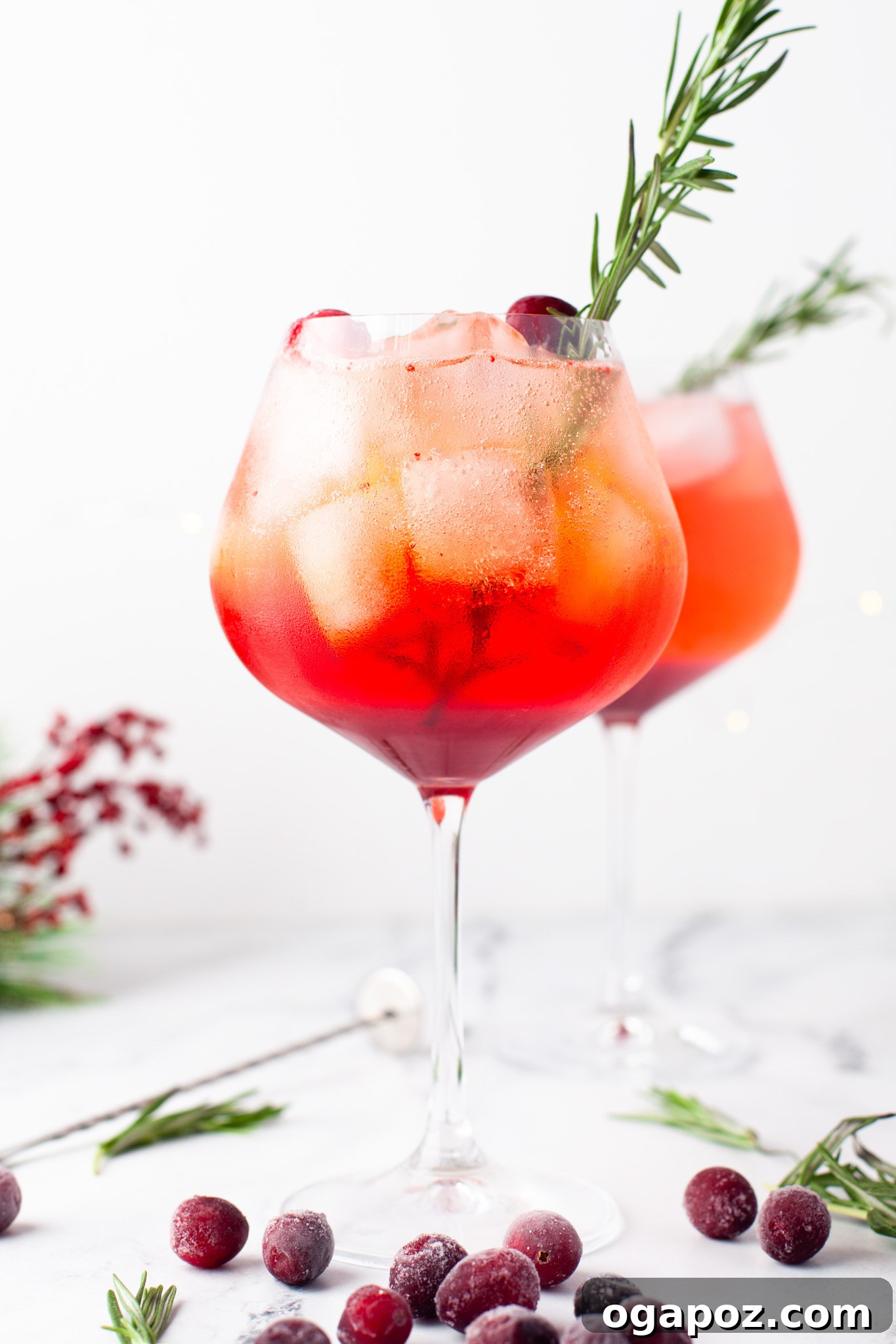 A vibrant Cranberry Aperol Spritz with a sprig of rosemary against a soft background, ready for a festive toast.