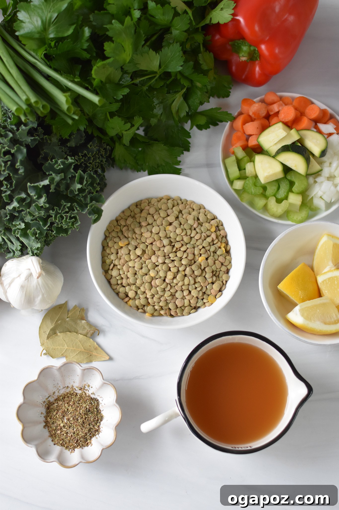 Hearty Tuscan Lentil Stew 3 Various fresh ingredients for Italian Style Lentil Soup laid out on a cutting board, including green lentils, carrots, celery, bell peppers, zucchini, kale, and herbs.