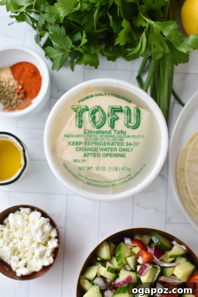 Mediterranean-Inspired Tofu Tacos 3 A spread of fresh ingredients including tofu, olive oil, spices, tomatoes, cucumber, red onion, and herbs, ready for Mediterranean Style Tofu Tacos.