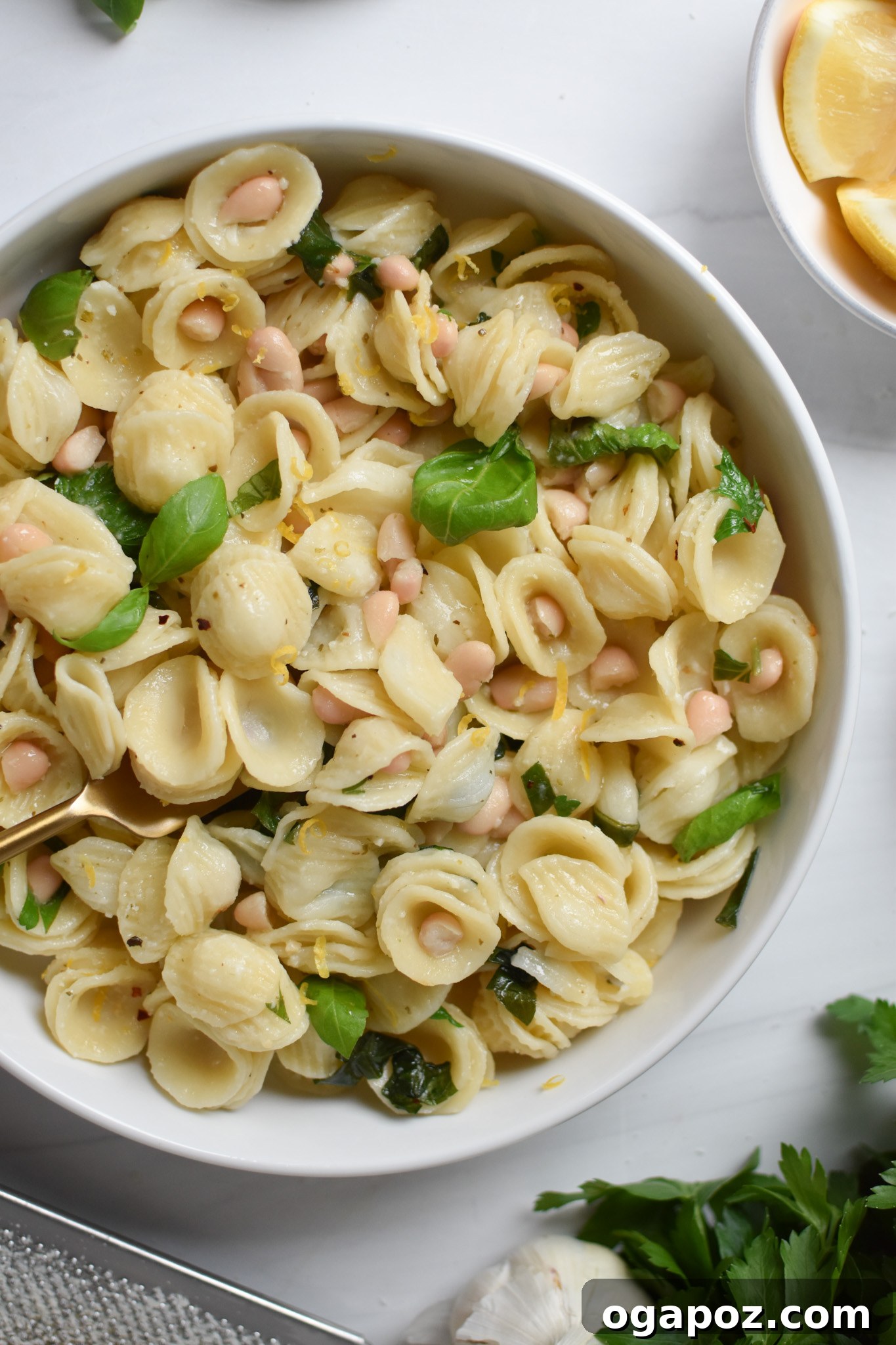 Bright Lemon Basil White Bean Pasta 2 A beautifully plated dish of Lemon Basil Pasta in a white bowl, garnished with fresh basil leaves and a lemon wedge.