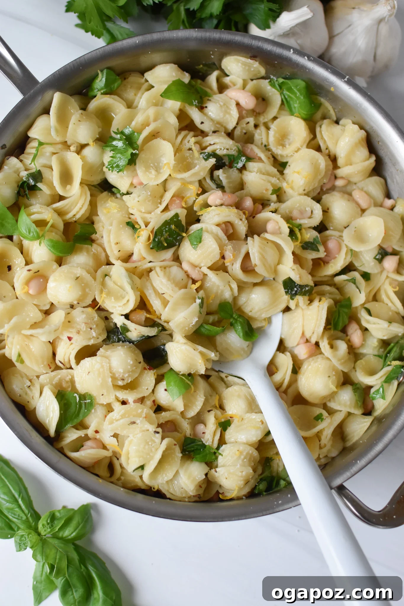 Bright Lemon Basil White Bean Pasta 4 Lemon Basil Pasta simmering in a large skillet, ready to be served, with a white spoon resting in it.