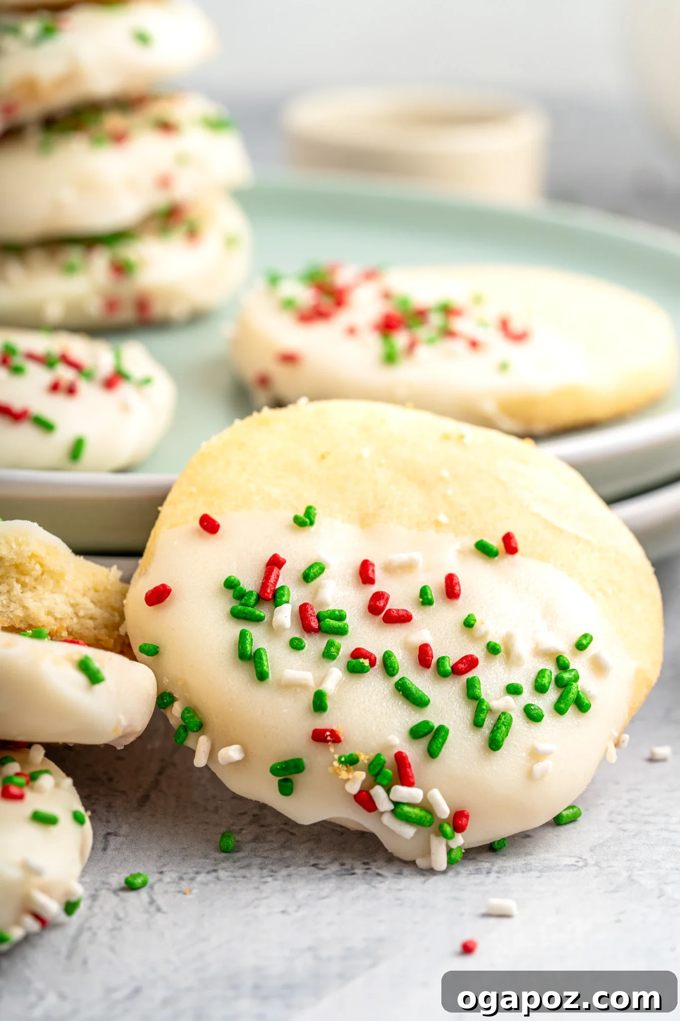 Buttery Christmas Shortbread Bliss 2 Festive Christmas Shortbread Cookies artfully arranged on a green plate, glistening with white chocolate and colorful sprinkles.