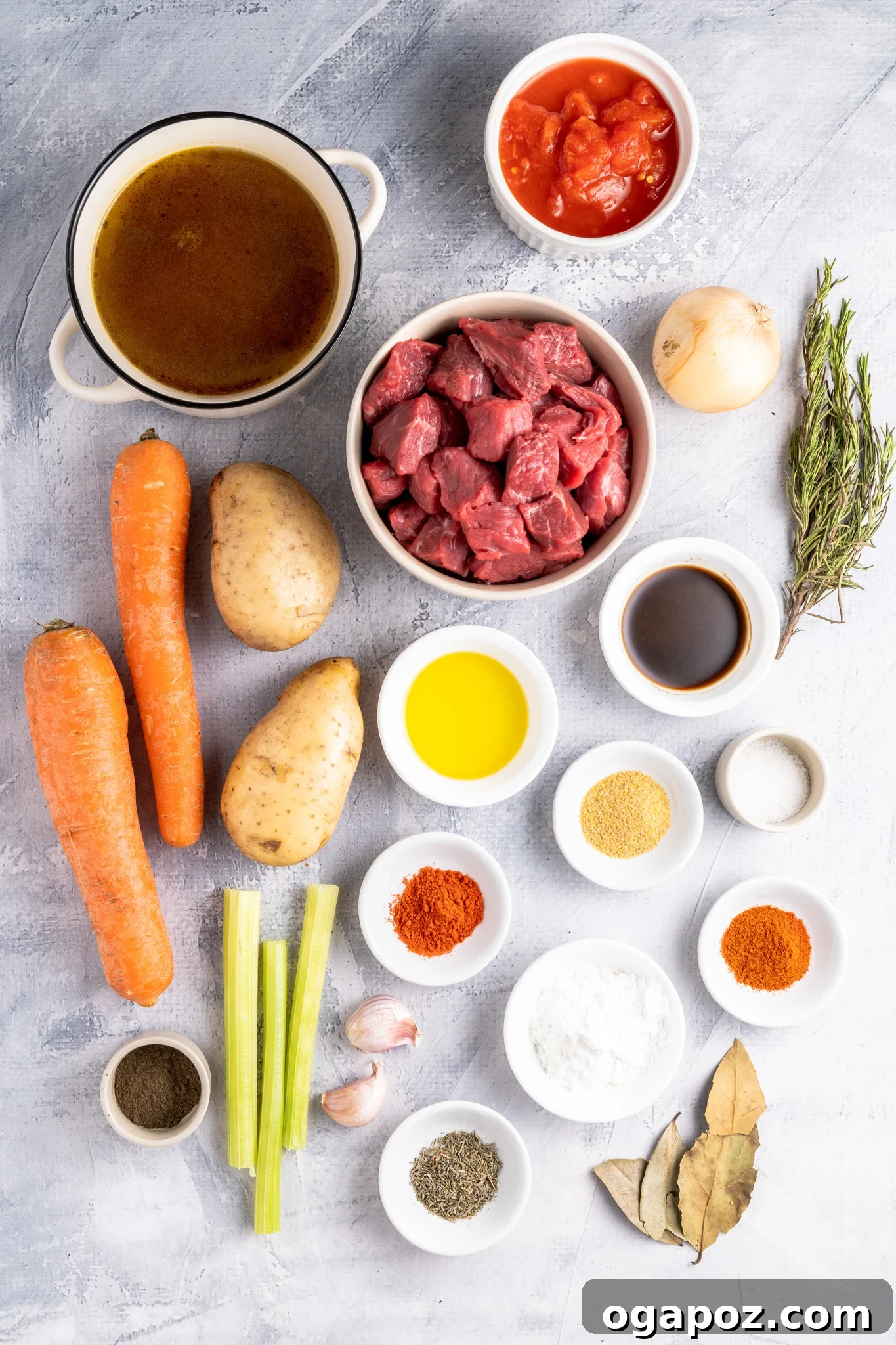 A collection of fresh ingredients laid out for Crock Pot Beef Stew: onions, carrots, potatoes, beef, herbs, and spices.