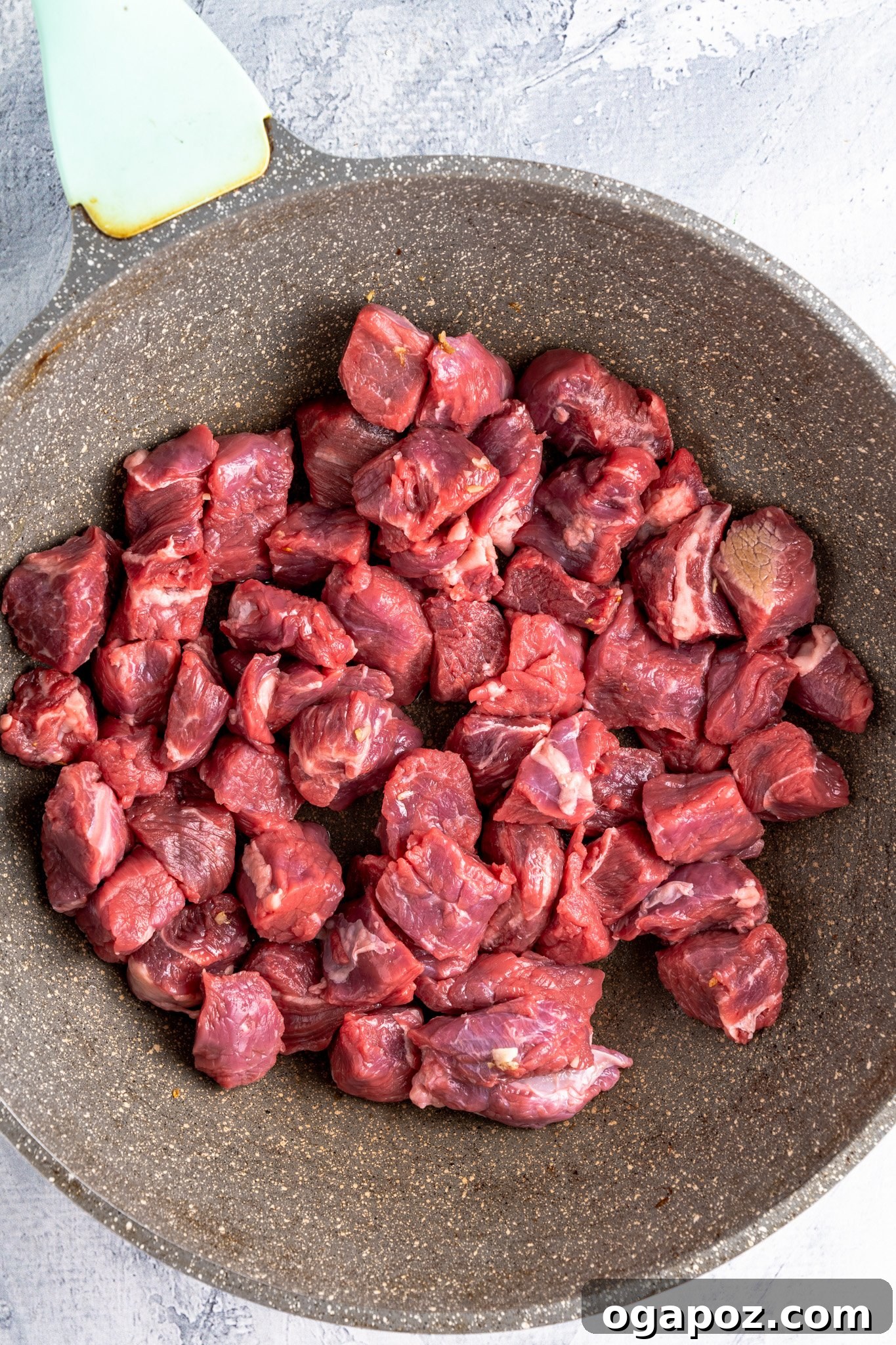 Diced chuck roast browning in a hot skillet, an essential step for flavorful Crock Pot Beef Stew.