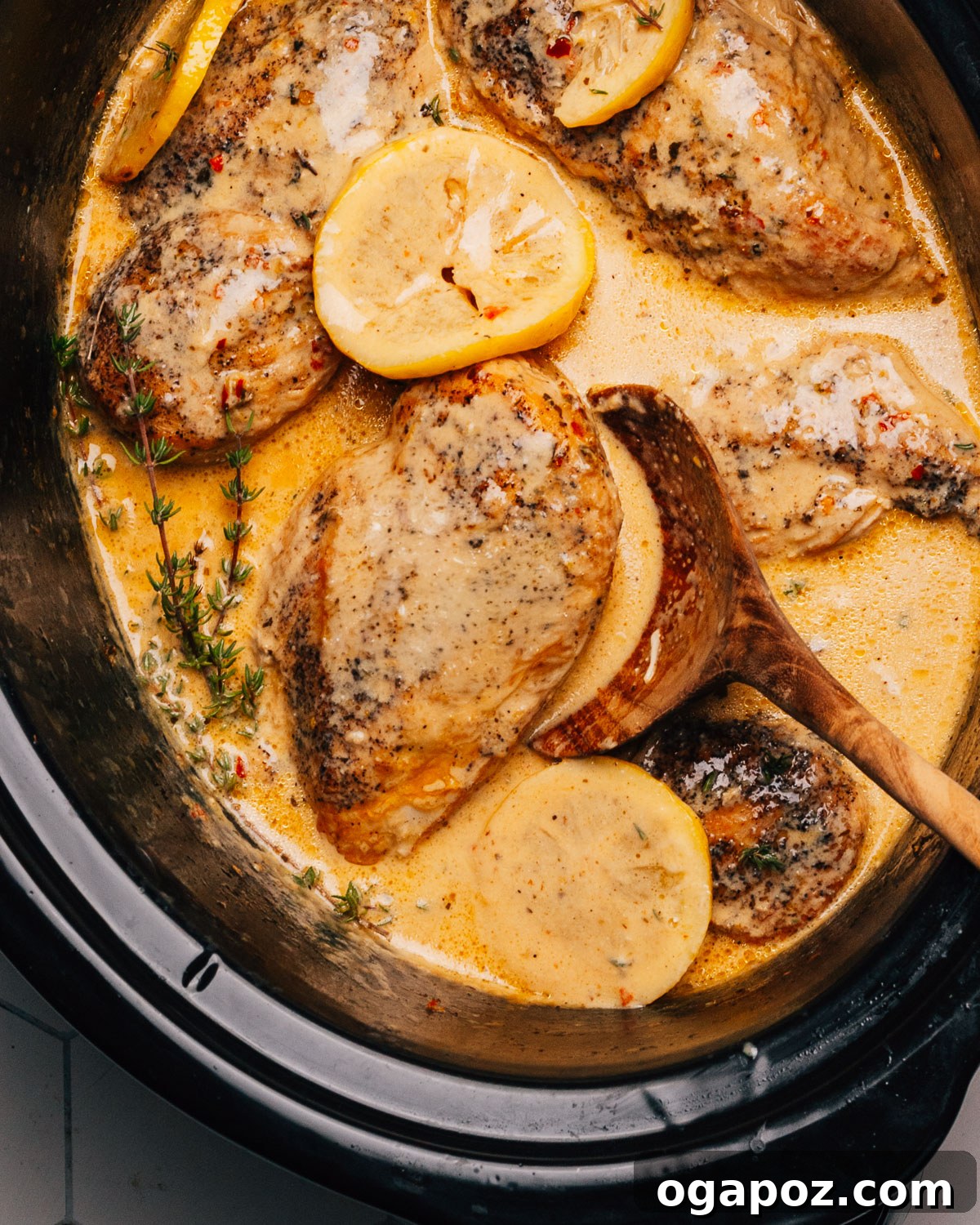 Lemony Slow Cooker Chicken 8 Finished Crockpot Lemon Chicken with a wooden spoon, garnished with parsley.