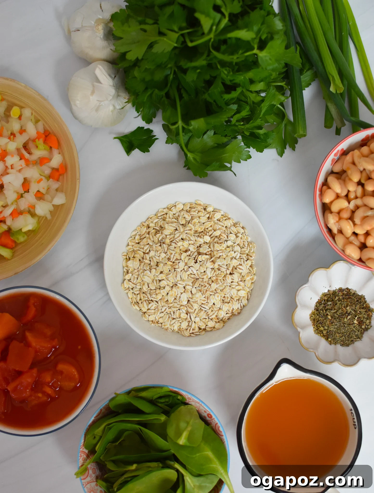 A flat lay of fresh ingredients for Vegetable Barley Soup, including carrots, celery, onion, garlic, barley, canned tomatoes, and various dried spices.
